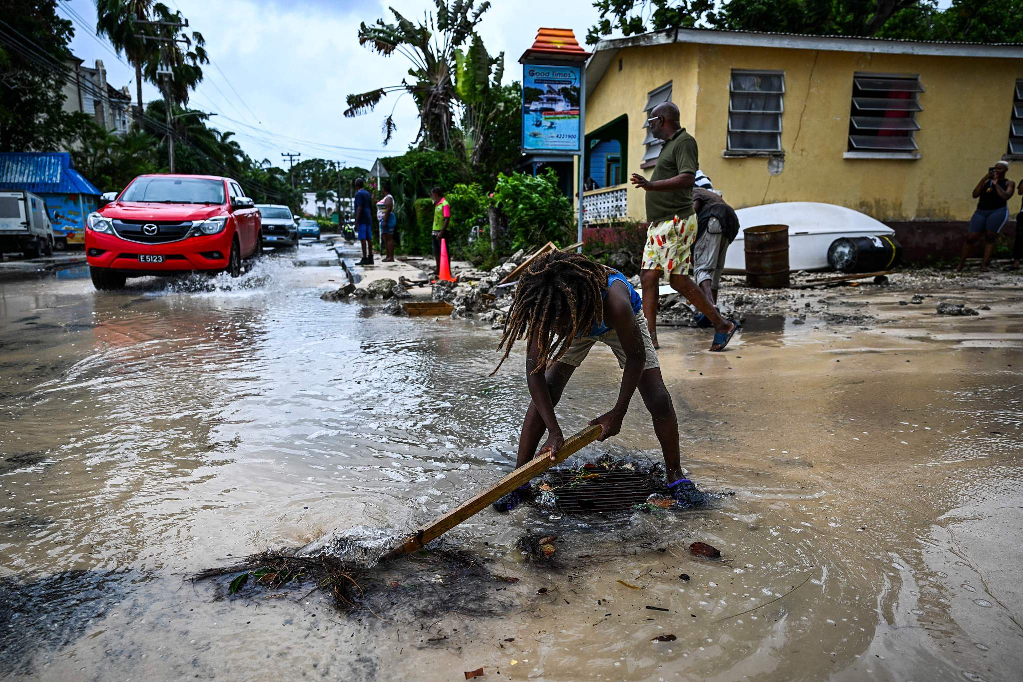 A boy clears rock from the street as it gets flooded after the hurricane Beryl passes in the parish of Saint James, Barbados, July 1, 2024. /CFP