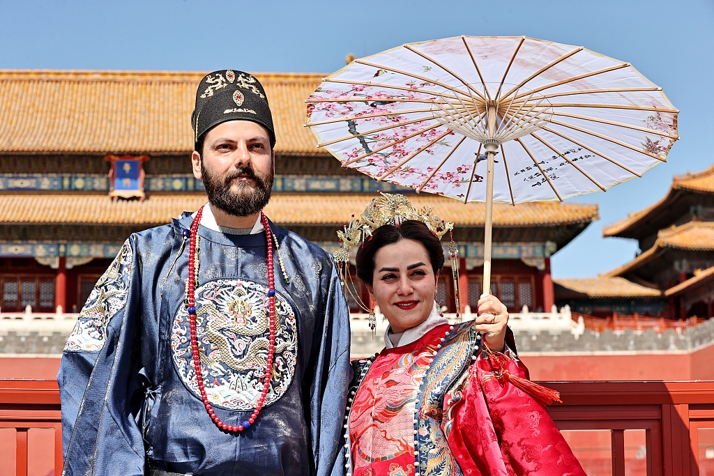 A photo taken on March 22, 2024 shows two foreign travelers wearing traditional Chinese attire and having their photo taken at the entrance to the Forbidden City in Beijing, China. /CFP