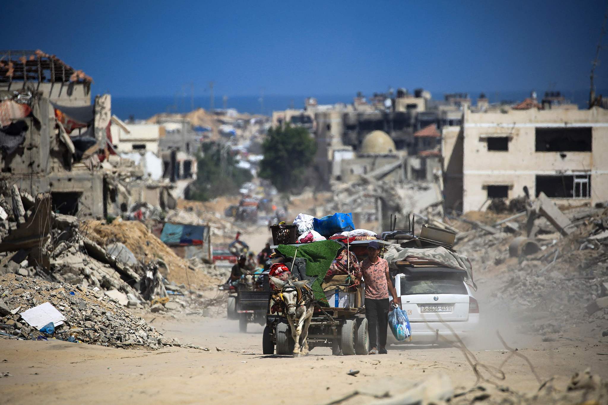 Palestinians walk and drive past buildings destroyed during previous Israeli bombardment, in Khan Yunis in the southern Gaza Strip, July 3, 2024. /CFP