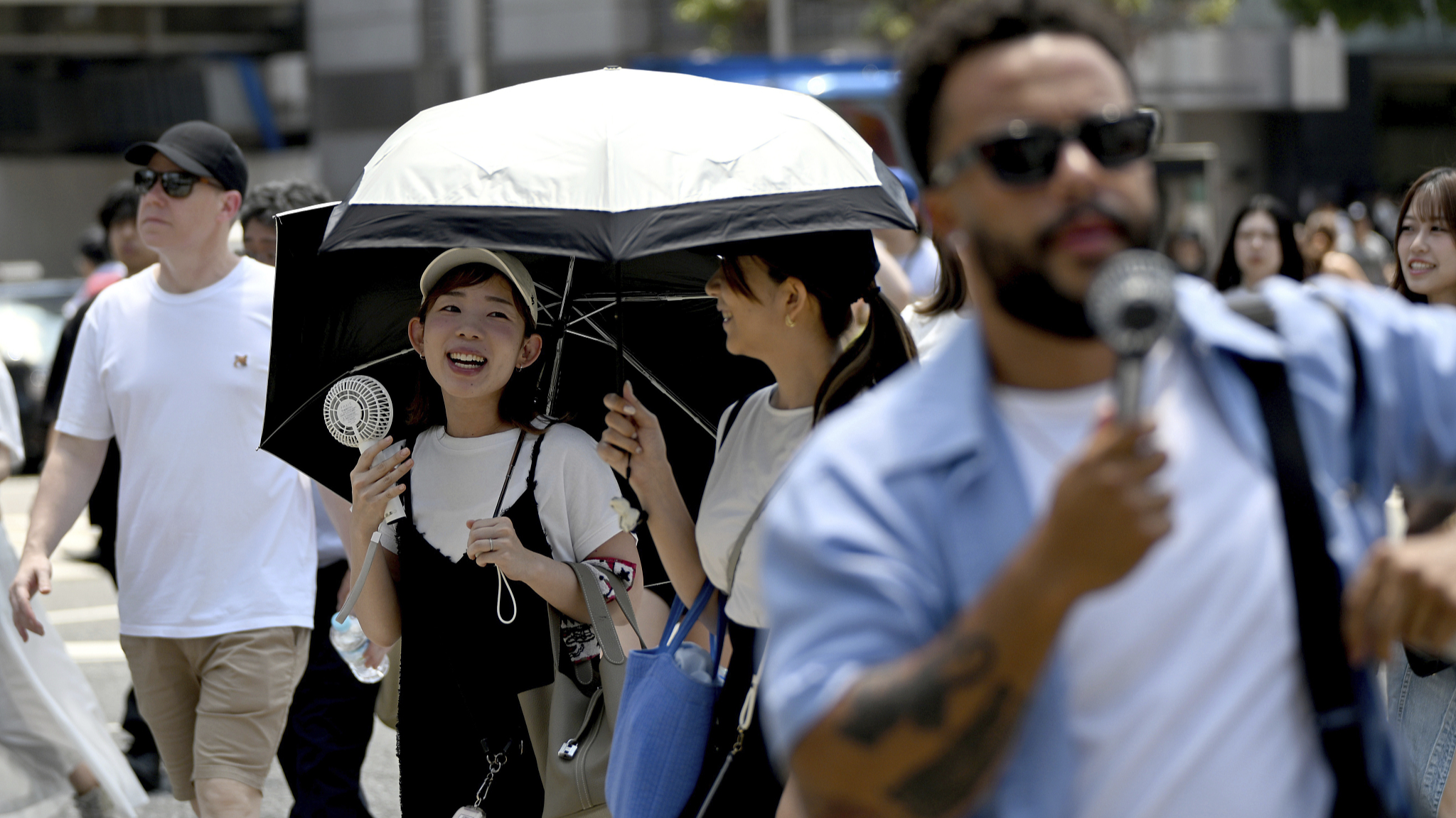 A pedestrian cools herself with a portable fan while crossing the intersection at Shibuya Scramble Crossing during a heat wave in Shibuya Ward, Tokyo, July 4, 2024. /CFP