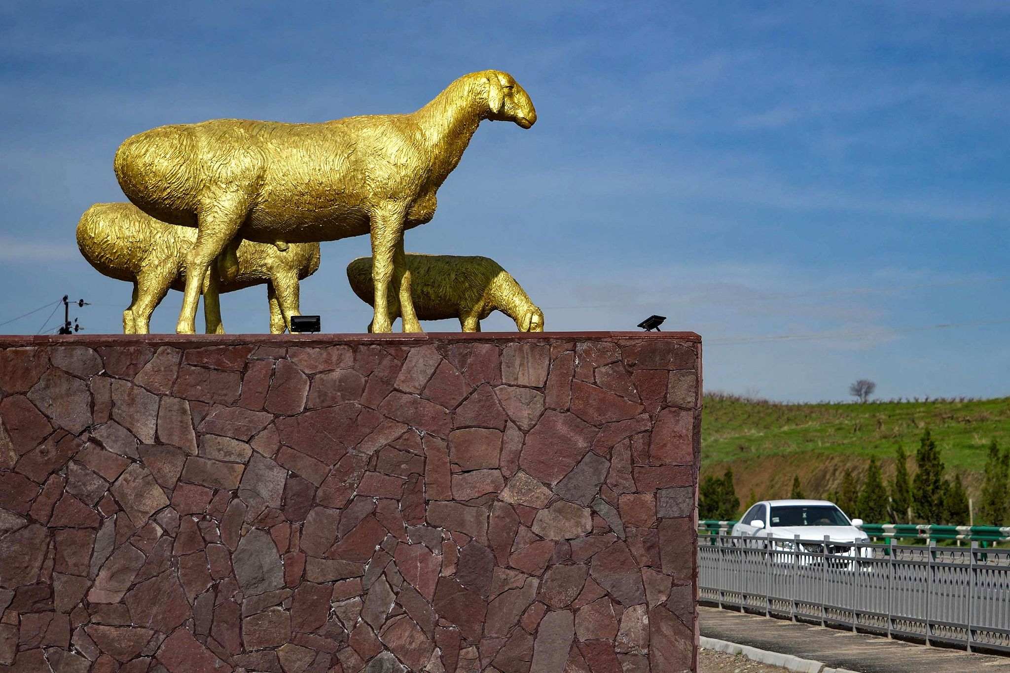 A car drives past a golden monument of three sheeps in Tajikistan March 27, 2024./ CFP
