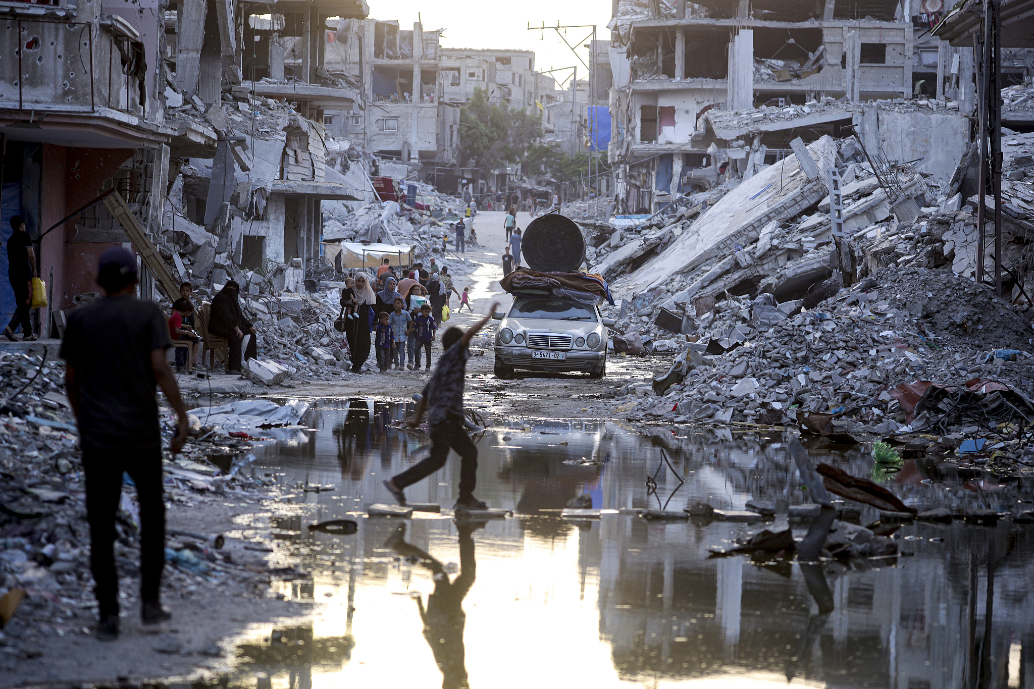 Palestinians displaced by the Israeli air and ground offensive in the Gaza Strip walk past sewage flowing into the streets of the southern town of Khan Younis, Gaza Strip, July 4, 2024. /CFP