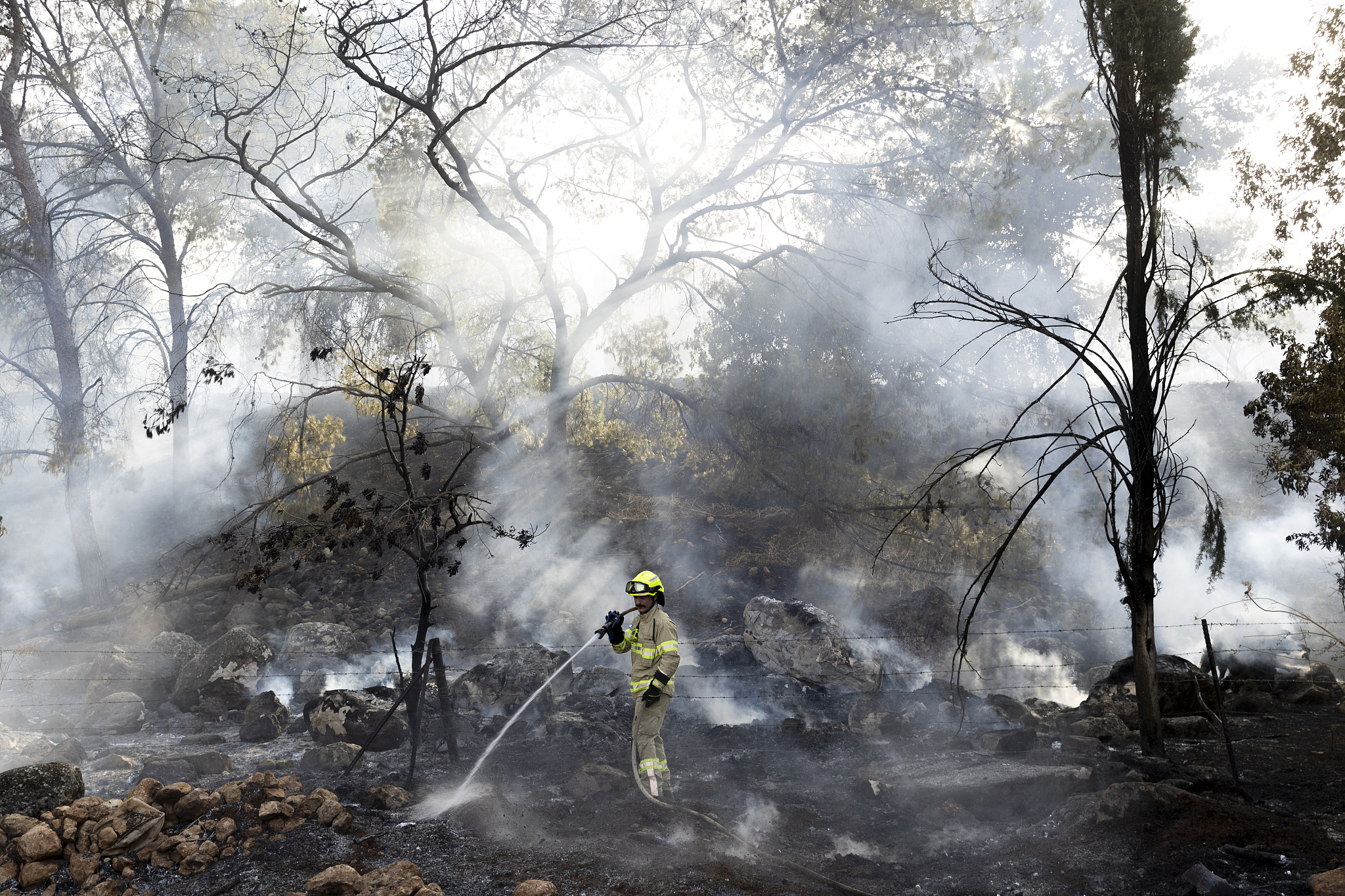 A firefighter douses a fire that broke out after a rocket strike fired from Lebanon, in northern Israel, July 4, 2024. Hezbollah claimed it fired 200 rockets and 20 drones at Israel after a senior officer was killed. /CFP