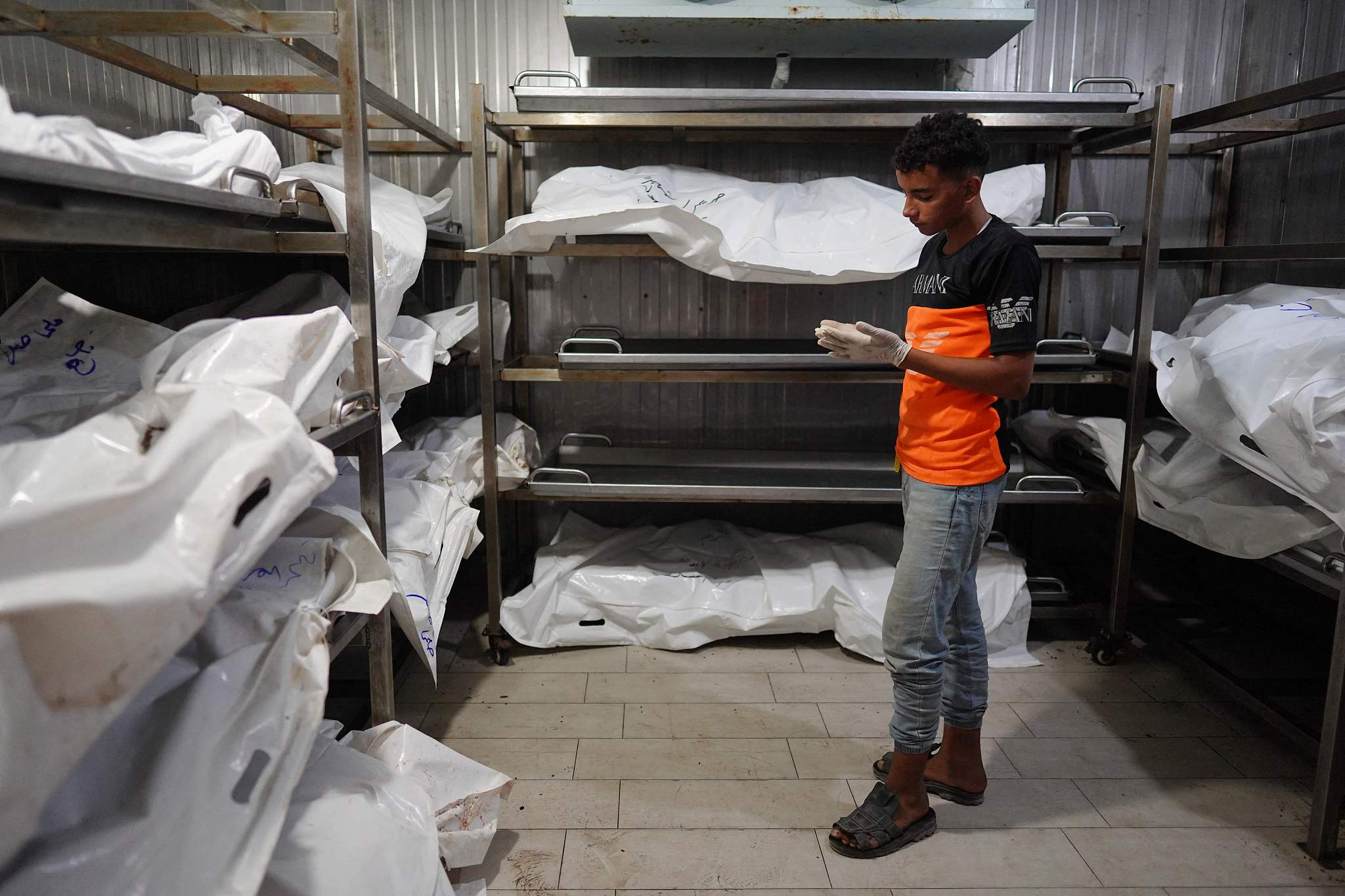 A Palestinian youth who works with his father at a morgue stands next to the bodies of unidentified people killed amid the continuing conflict between Israel and Hamas in the southern Gaza Strip, at the Nasser Hospital in Khan Yunis, July 5, 2024. /CFP