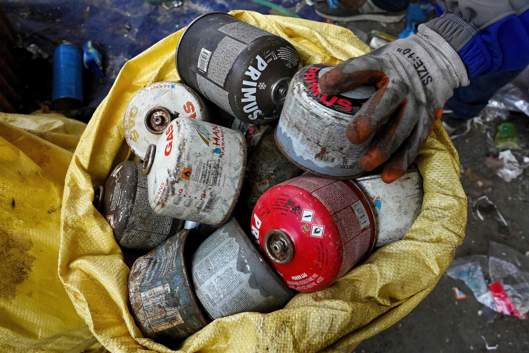 A worker collects used power gas cartridges in a sack with other waste materials retrieved from Mount Qomolangma to recycle in Kathmandu, Nepal, June 12, 2024. /CFP