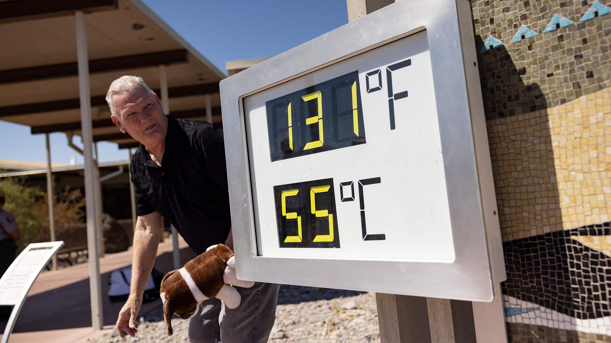 A visitor reacts as he poses next to a thermometer reading 