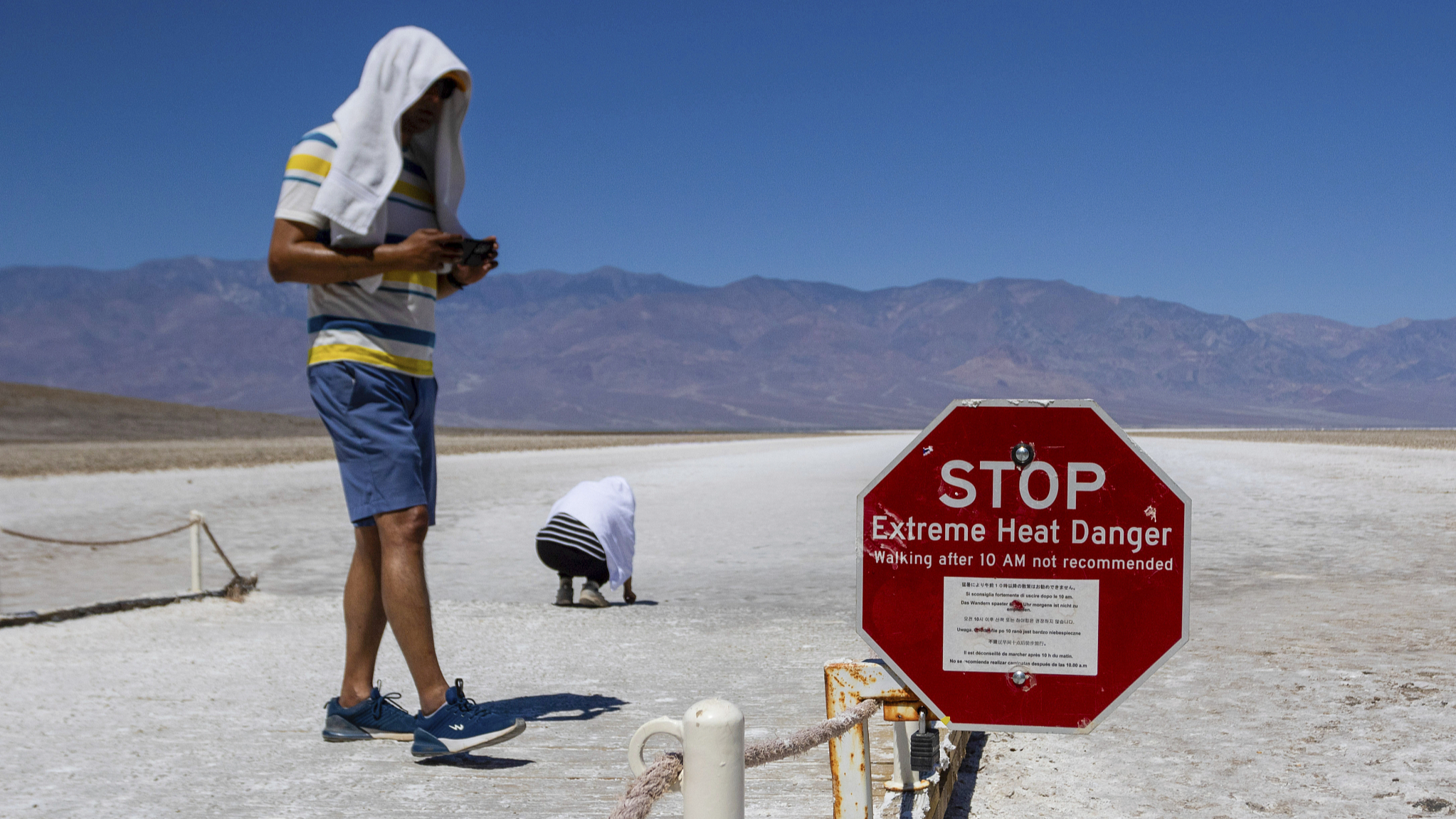 Two people cover themselves in white towels as they walk around Badwater Basin in Death Valley National Park, California, the U.S., July 7, 2024. /CFP