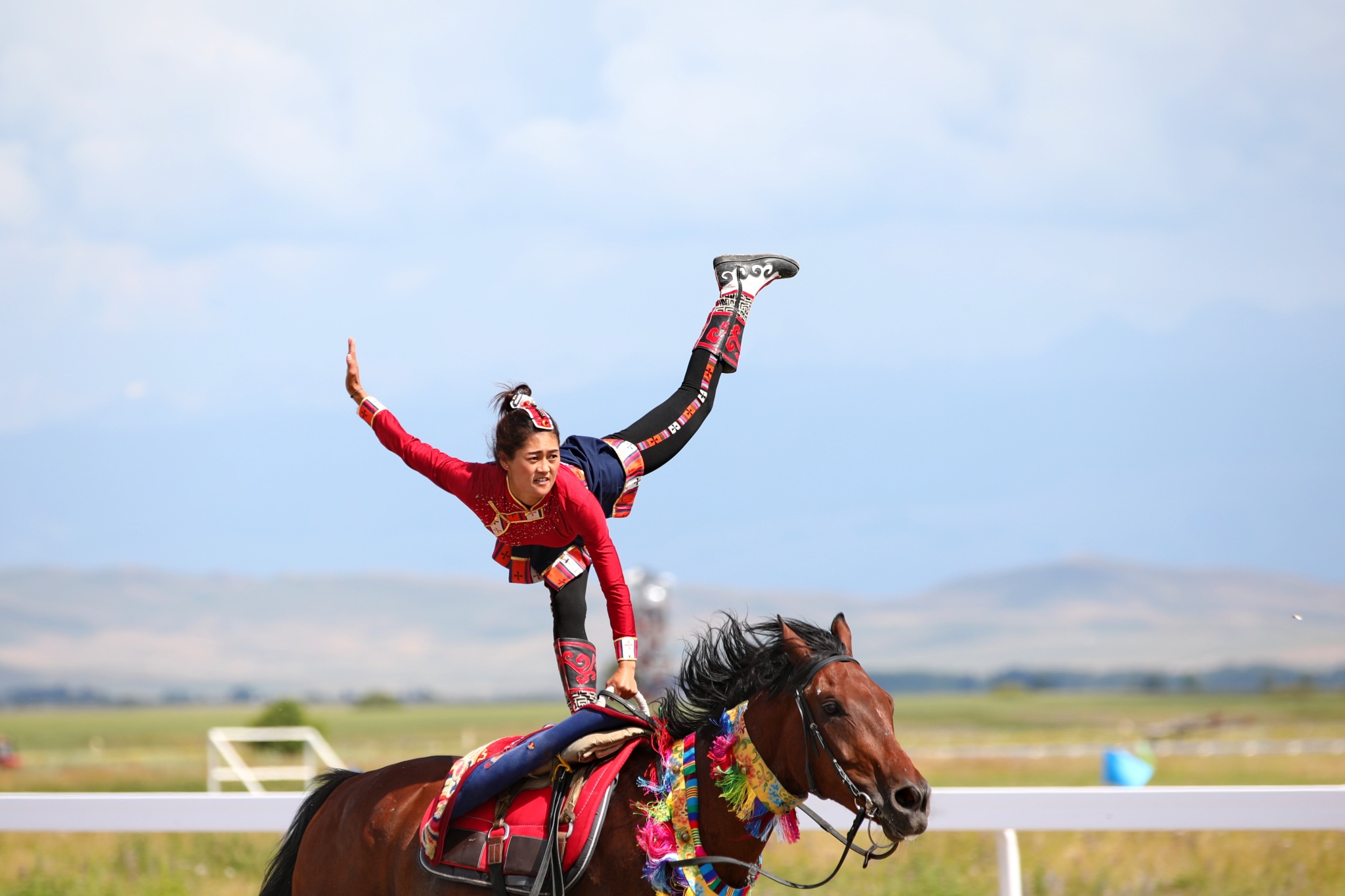 A female rider performs stunts on horseback during the equestrian events of China's 12th National Traditional Games of Ethnic Minorities held in Xinjiang on July 8, 2024. /CFP