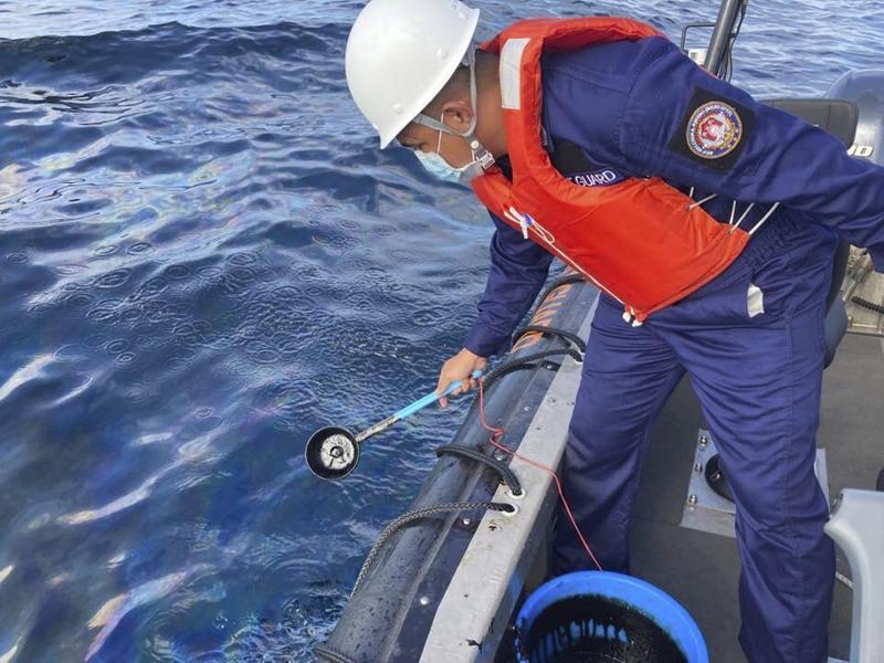 In this handout photo provided by the Philippine Coast Guard, coast guard personnel collect water samples from an oil spill in the waters off Naujan, Oriental Mindoro, central Philippines, March 2, 2023. /AP