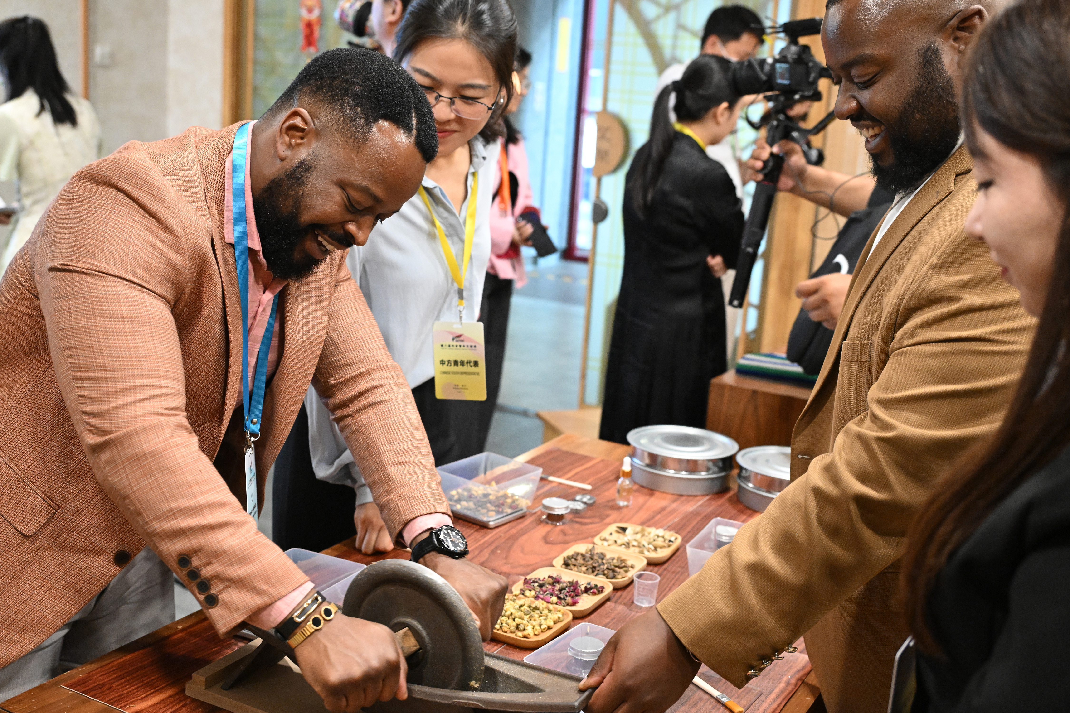 A young representative experiences the grinding of traditional Chinese medicine at the 8th China-Africa Youth Festival, Beijing, May 20, 2024. /CFP