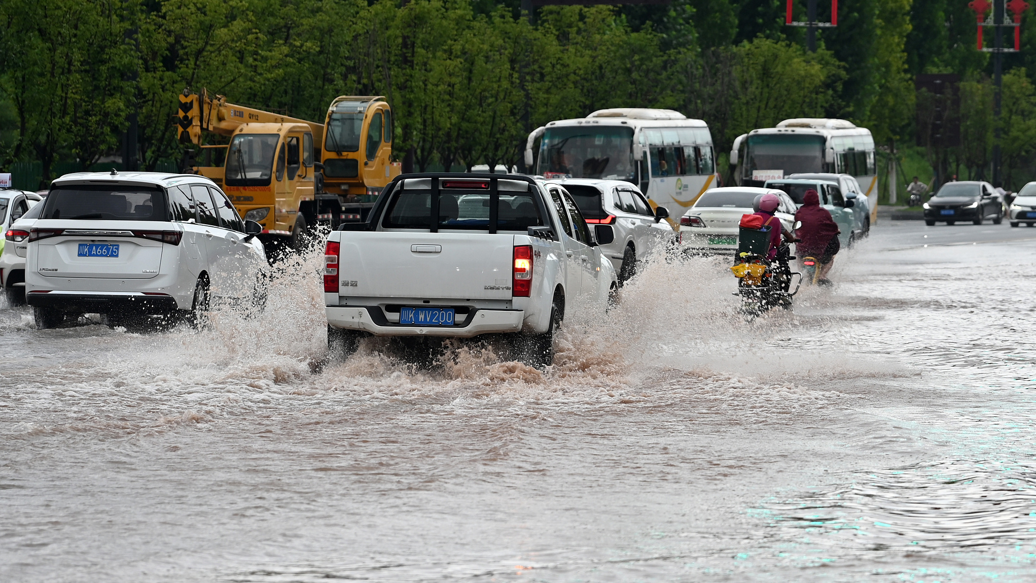 Short-term heavy rainfall has caused waterlogging on some roads in the main urban area of Neijiang City, southwest China's Sichuan Province, with residents braving the rain to go out, July 13, 2024. /CFP