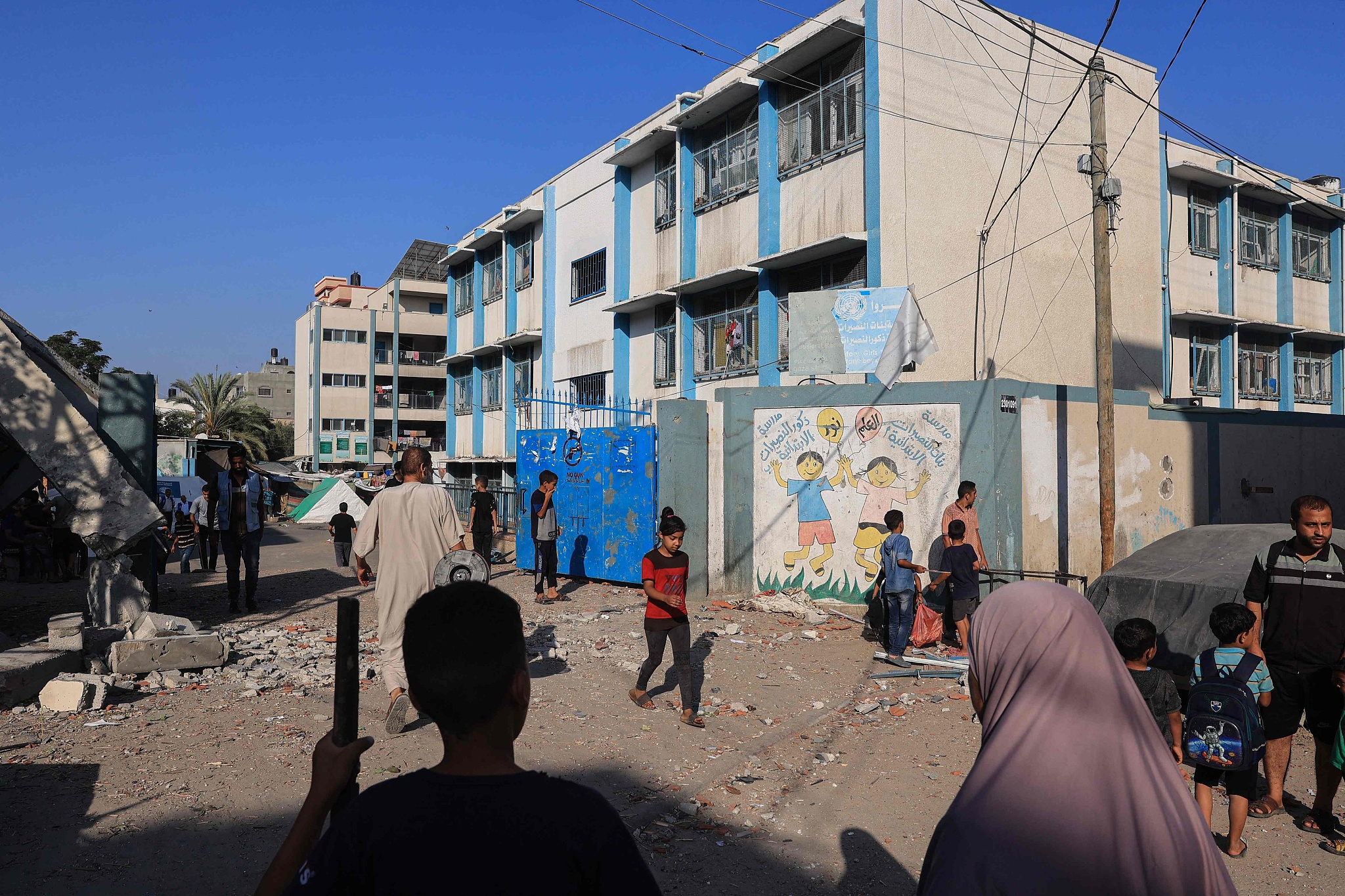 People walk past debris at a UN-run school after Israeli bombardment in Nuseirat in the central Gaza Strip on July 9, 2024. /CFP