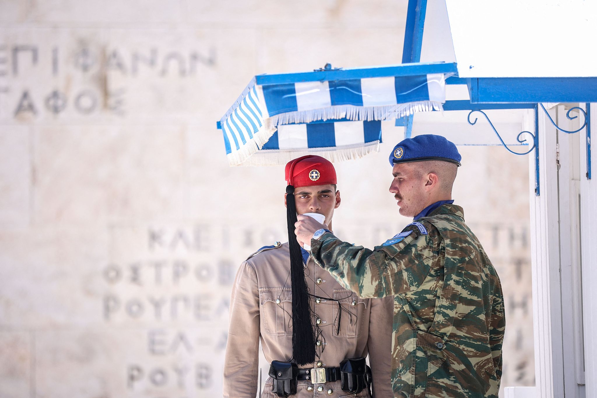 An officer gives water to a presidential guard member standing in front of the Tomb of the Unknown Soldier in Syntagma Square, Athens, Greece, July 12, 2024. /CFP