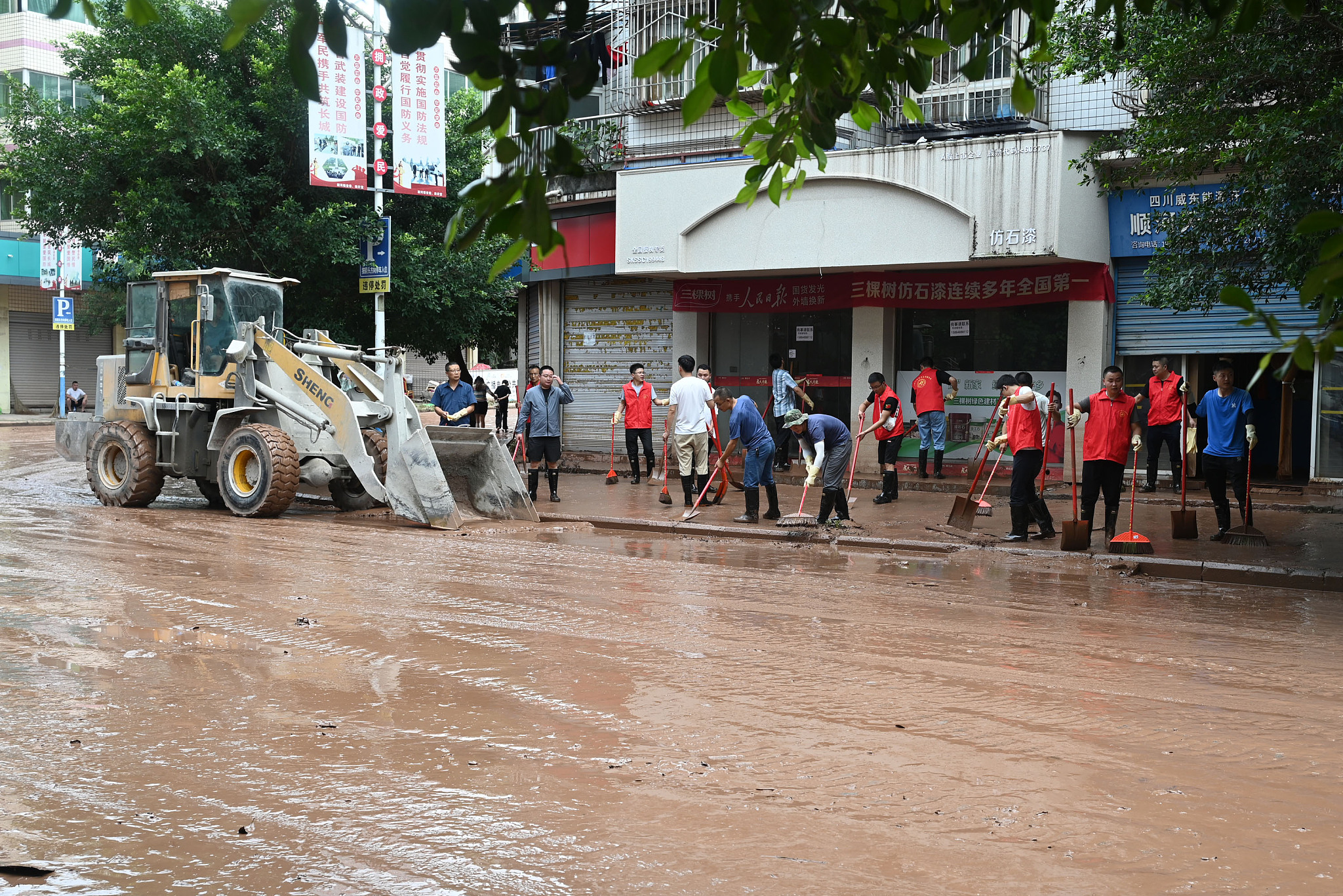 Volunteers clear mud from the streets in Neijiang City, southwest China's Sichuan Province, July 15, 2024. /CFP