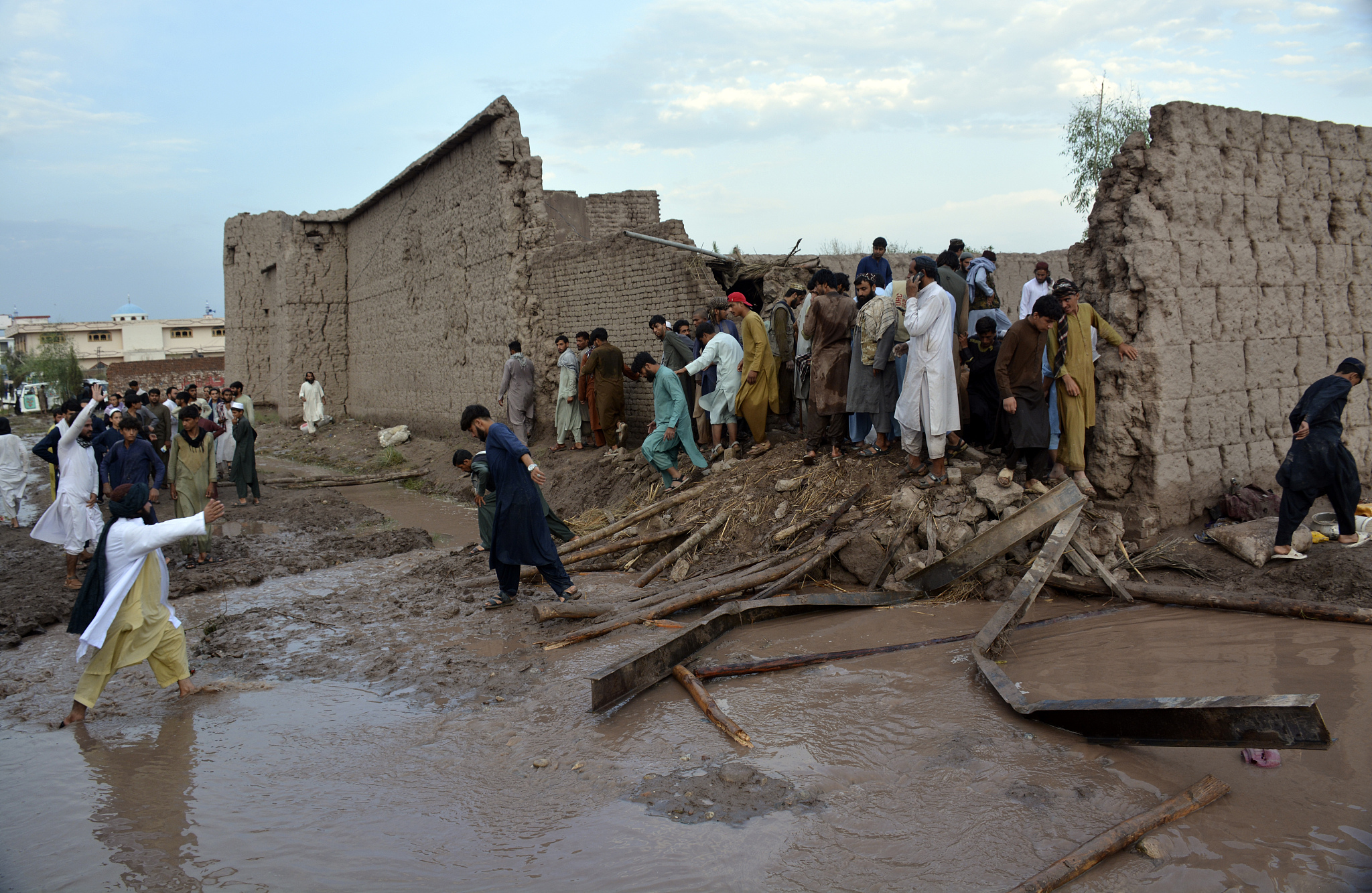 People gather to clear the rubble of a house partially damaged by a landslide due to heavy rainfall in Surkhroad district, Nangarhar province, Afghanistan, July 15, 2024. /CFP
