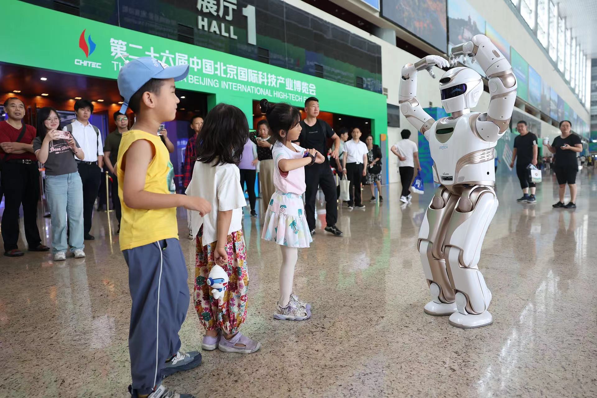 A humanoid robot interacts with children at the 26th China Beijing International High-tech Expo, Beijing, China, July 14, 2024. /CFP