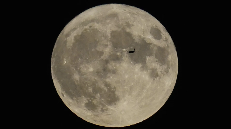 A plane passes in front of the moon, August 30, 2023. /AP