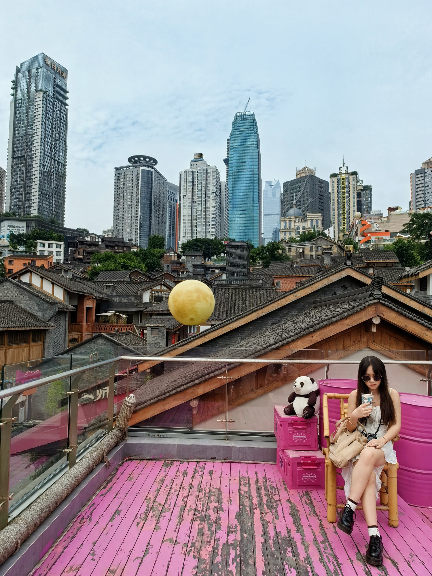 A woman poses for a photo on a rooftop of the Eighteen Stairs district of Chongqing on July 11, 2024. /CGTN
