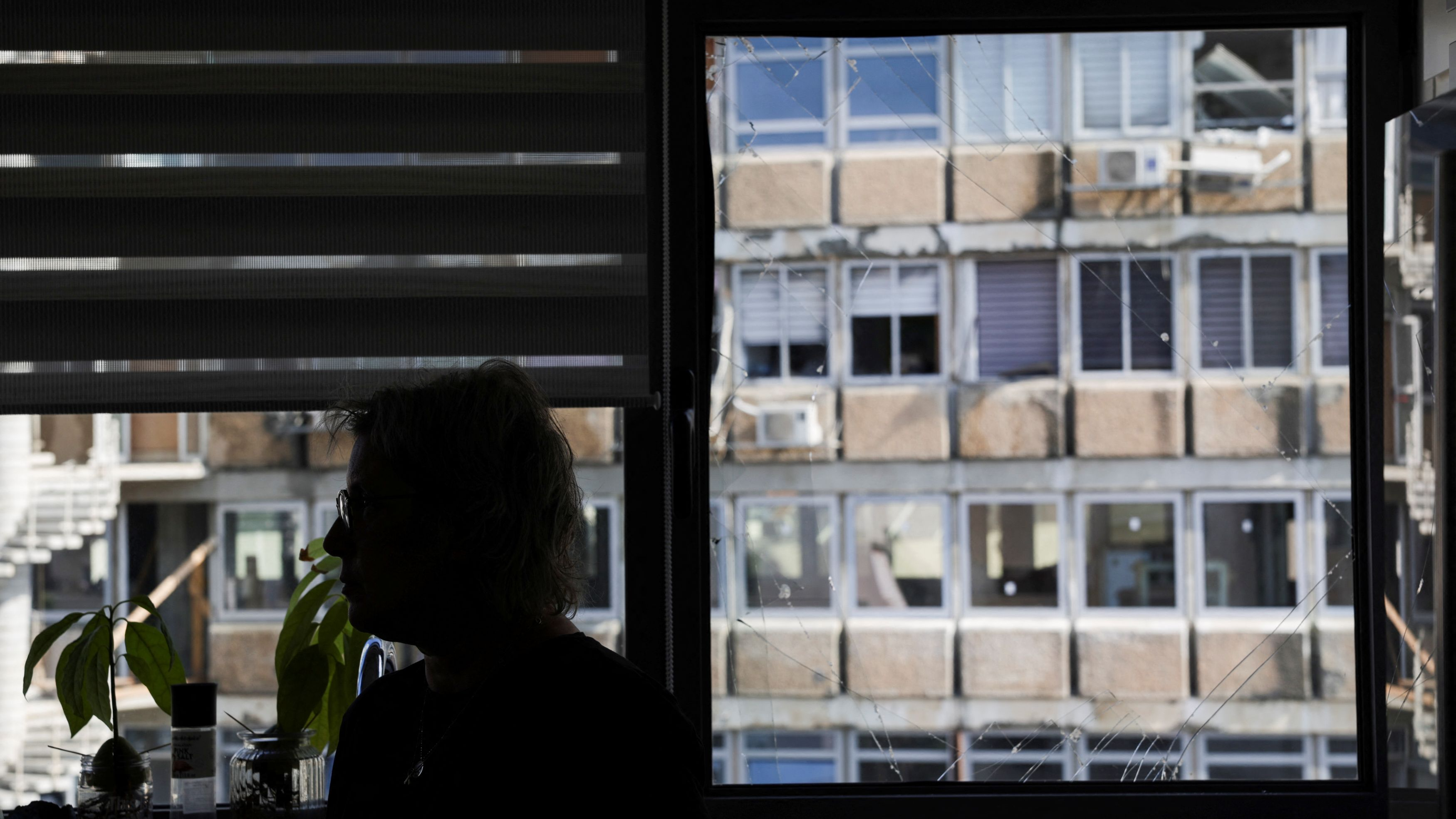 A woman stands next to a broken window pane near the site of an explosion in Tel Aviv, Israel, July 19, 2024. /Reuters