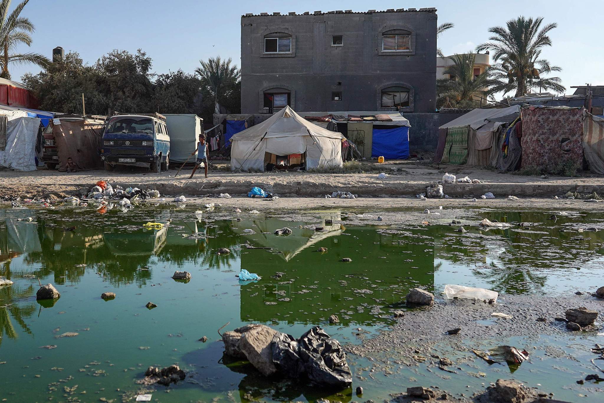Tents are set up as temporary shelters for displaced Palestinians on a street covered with stagnant wastewater in Deir el-Balah in the central Gaza Strip, July 19, 2024. /CFP