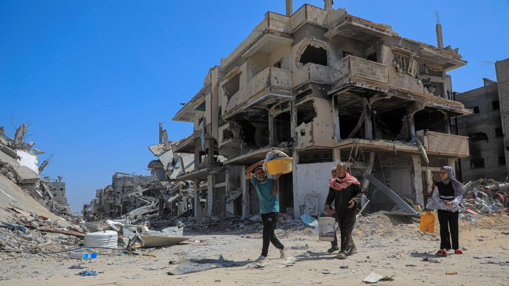 Palestinians walk past buildings destroyed in Israeli strikes in the southern Gaza Strip city of Khan Younis, April 12, 2024. /Xinhua