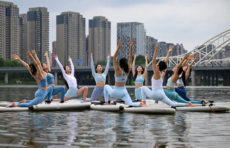Yoga teachers demonstrate paddleboard yoga on the Hunhe River in Shenyang, Liaoning Province on July 24, 2024. /CFP
