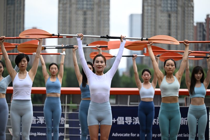 Yoga teachers hold up paddles while balancing on paddleboards during a paddleboard yoga demonstration on the Hunhe River in Shenyang, Liaoning Province on July 24, 2024. /CFP