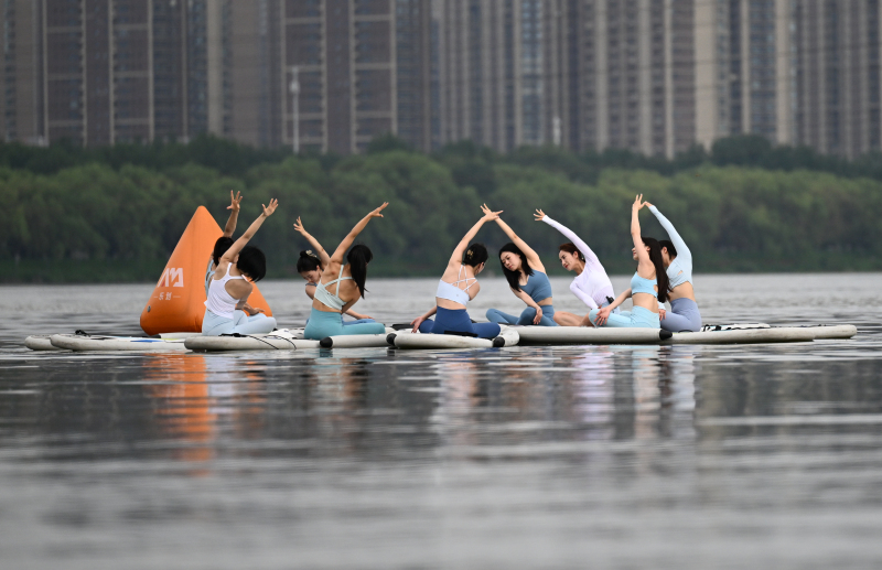 Yoga teachers demonstrate paddleboard yoga on the Hunhe River in Shenyang, Liaoning Province on July 24, 2024. /CFP