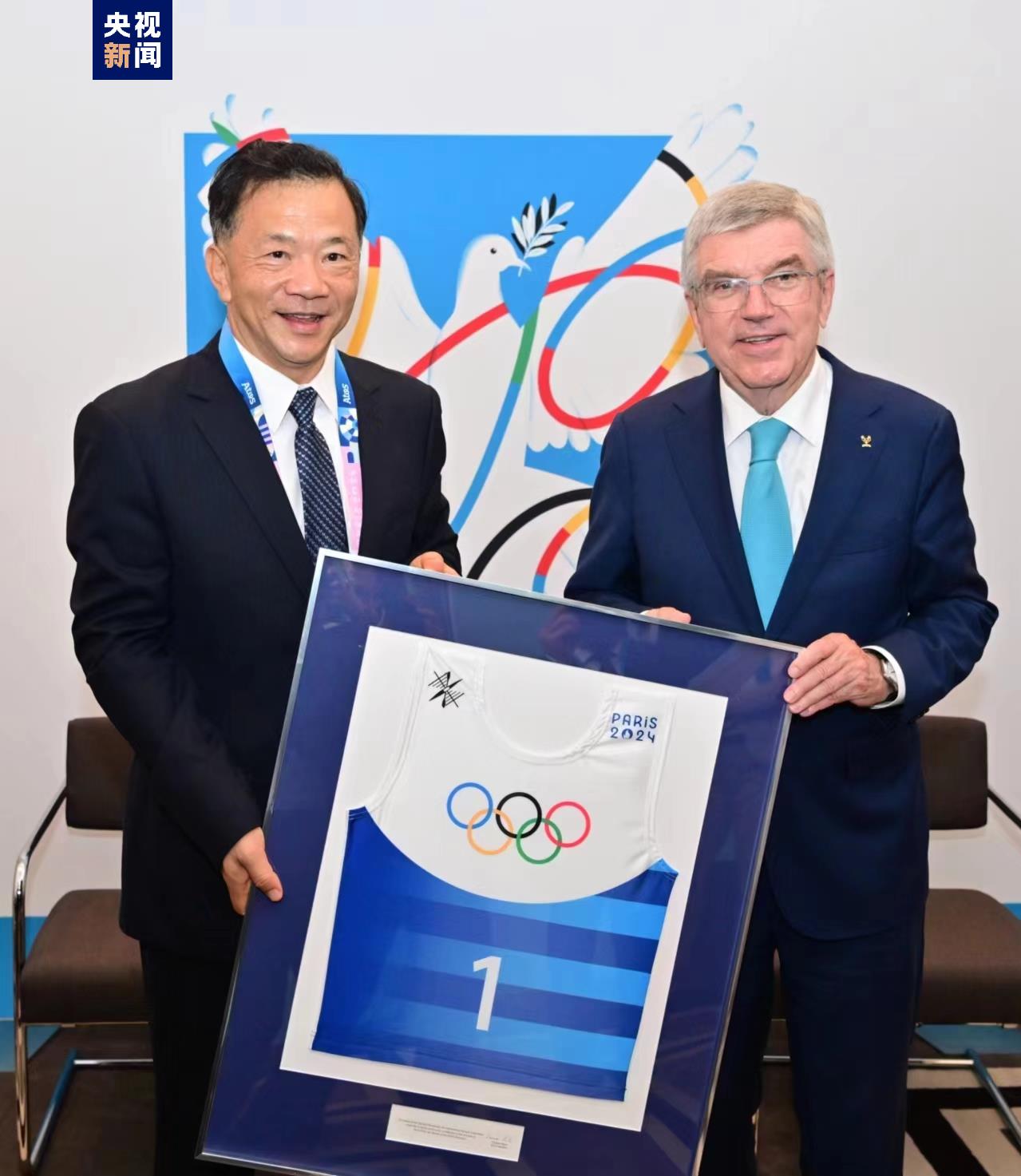 CMG President Shen Haixiong (L) and IOC President Thomas Bach jointly display a Paris 2024 No. 1 jersey. /CMG