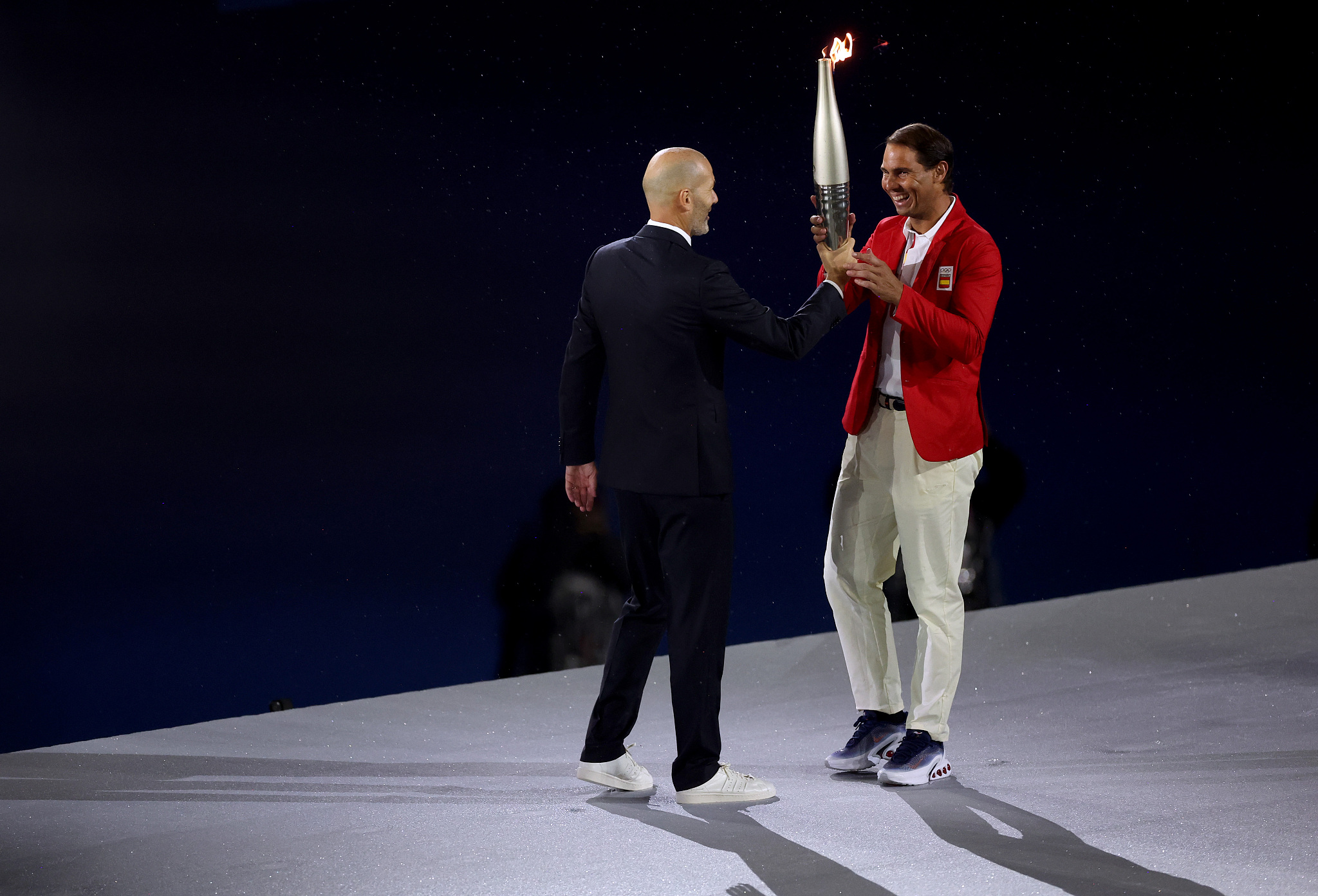 Former French football player Zinedine Zidane hands the Olympic torch to Spanish tennis player Rafael Nadal during the opening ceremony of the Paris 2024 Olympic Games in Paris, France, July 26, 2024. /CFP