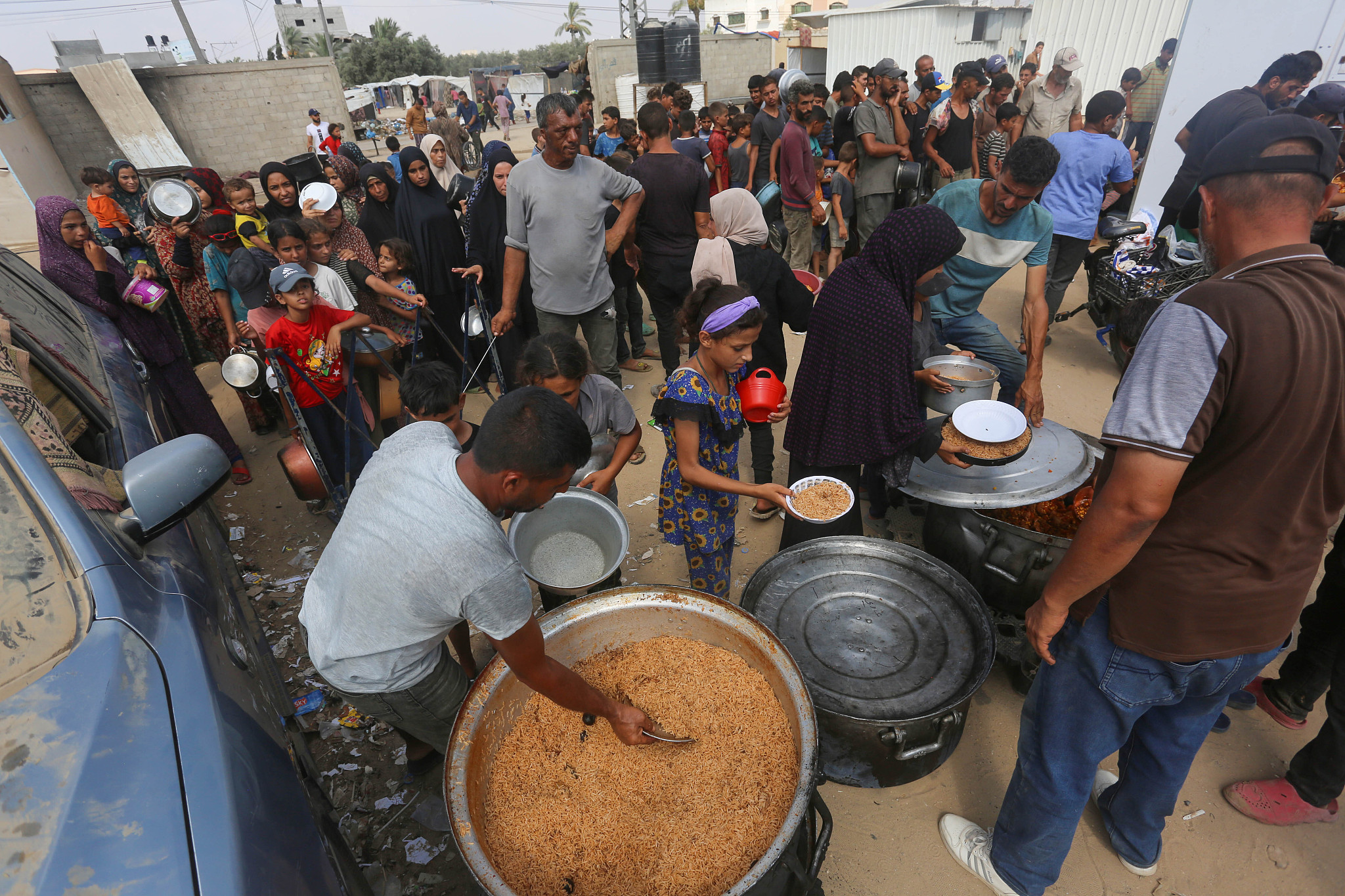 Palestinians, including children, queue to receive food distributed by charitable organizations as they are unable to obtain many vital needs, including basic food supplies, due to the total embargo imposed by Israeli forces on the territory in Deir Al Balah, Gaza, July 24, 2024. /CFP