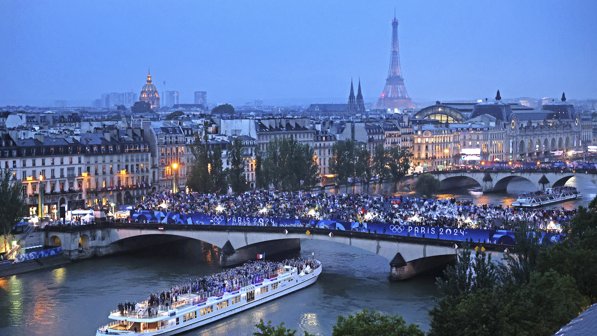 Spectators look on as athletes from Team France cruise on the Seine River during the opening ceremony of the 2024 Summer Olympics, July 26, 2024 in Paris, France. /CFP