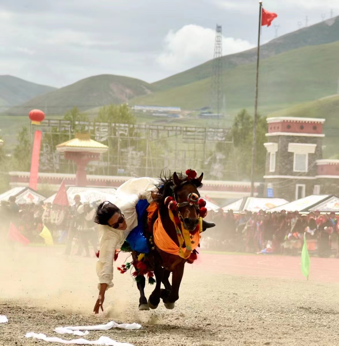 A man picks up khata scarves while riding at the opening of the Yushu Horse Racing Festival in Yushu City, Yushu Tibetan Autonomous Prefecture, northwest China's Qinghai Province, July 25, 2024. /Courtesy of Publicity Department of the CPC Yushu Municipal Committee