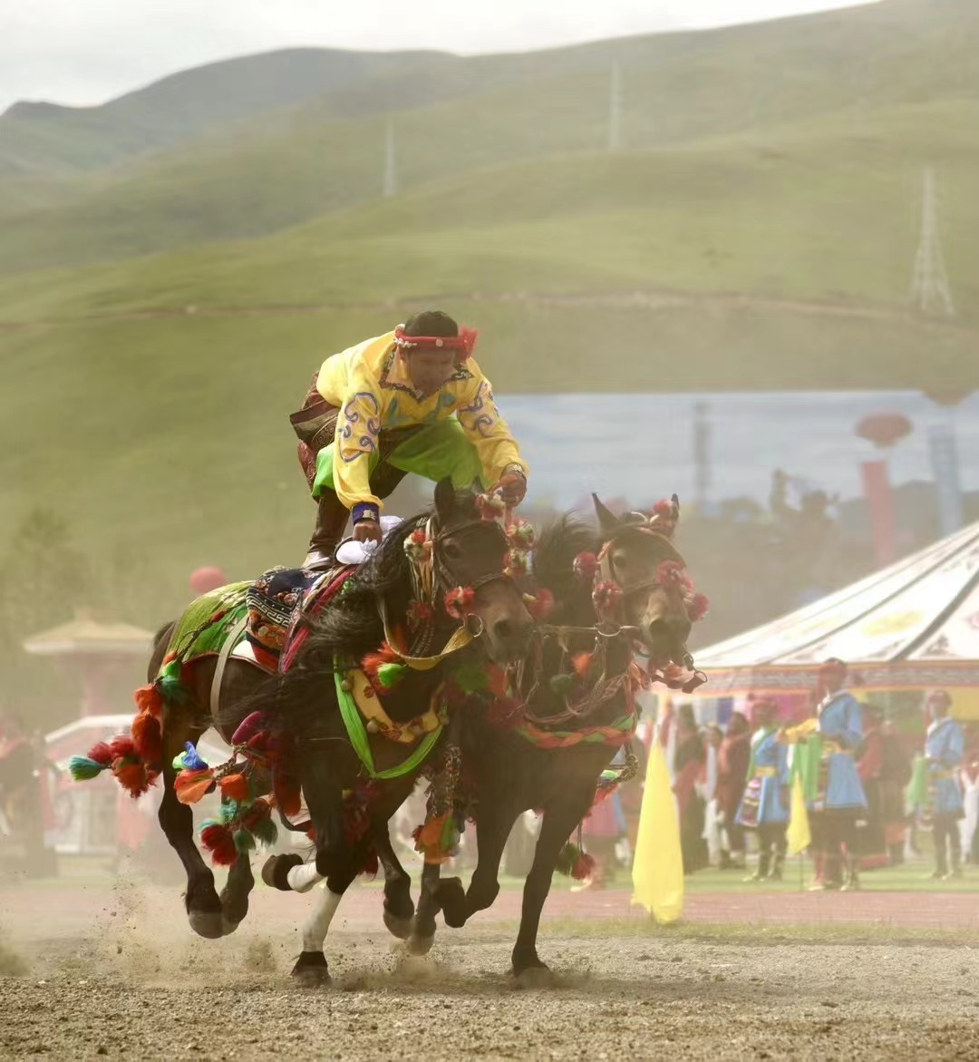 A man rides on two horses at the opening of the Yushu Horse Racing Festival in Yushu City, Yushu Tibetan Autonomous Prefecture, northwest China's Qinghai Province, July 25, 2024. /Courtesy of Publicity Department of the CPC Yushu Municipal Committee