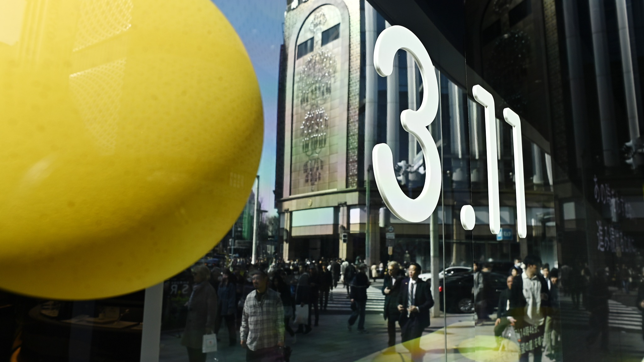 View of reflection of people in store window of Wako building displaying information and a video support message at the most luxurious shopping district of Tokyo, Japan, on March 11, 2024. /CFP