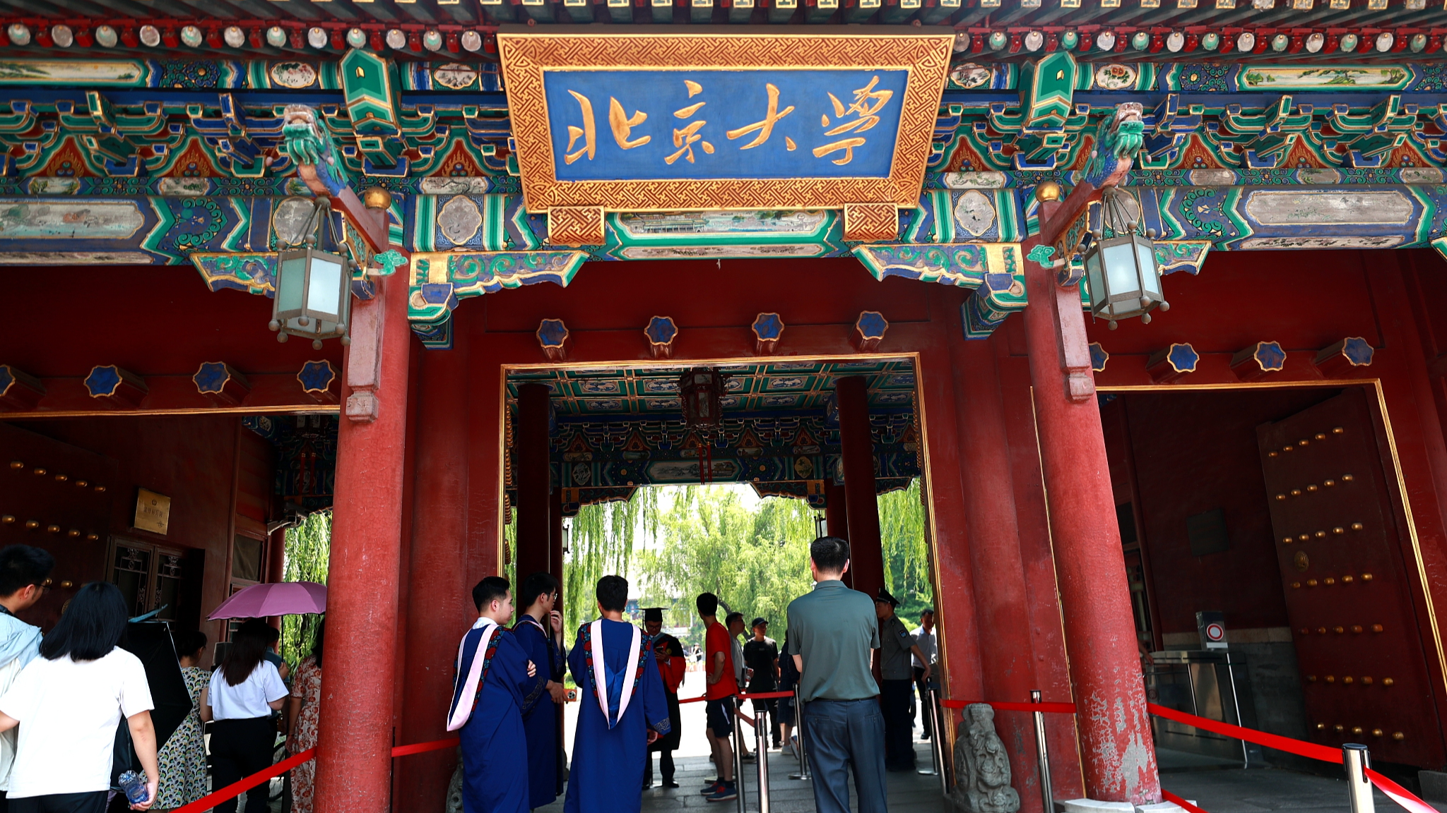 Para wisudawan mengenakan toga dan topi berfoto untuk mengenang kelulusan mereka di pintu masuk Universitas Peking, Beijing, Tiongkok, 19 Juni 2024. /CFP