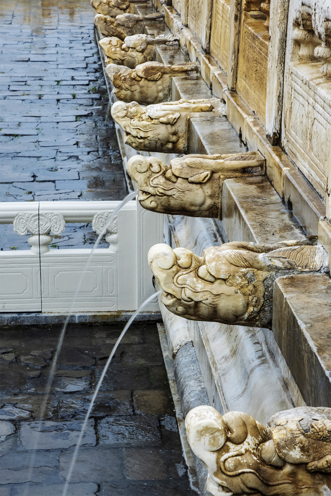 Rainwater spouts from the mouths of stone dragon heads at the Palace Museum in Beijing during a heavy rain on July 30, 2024. /CFP