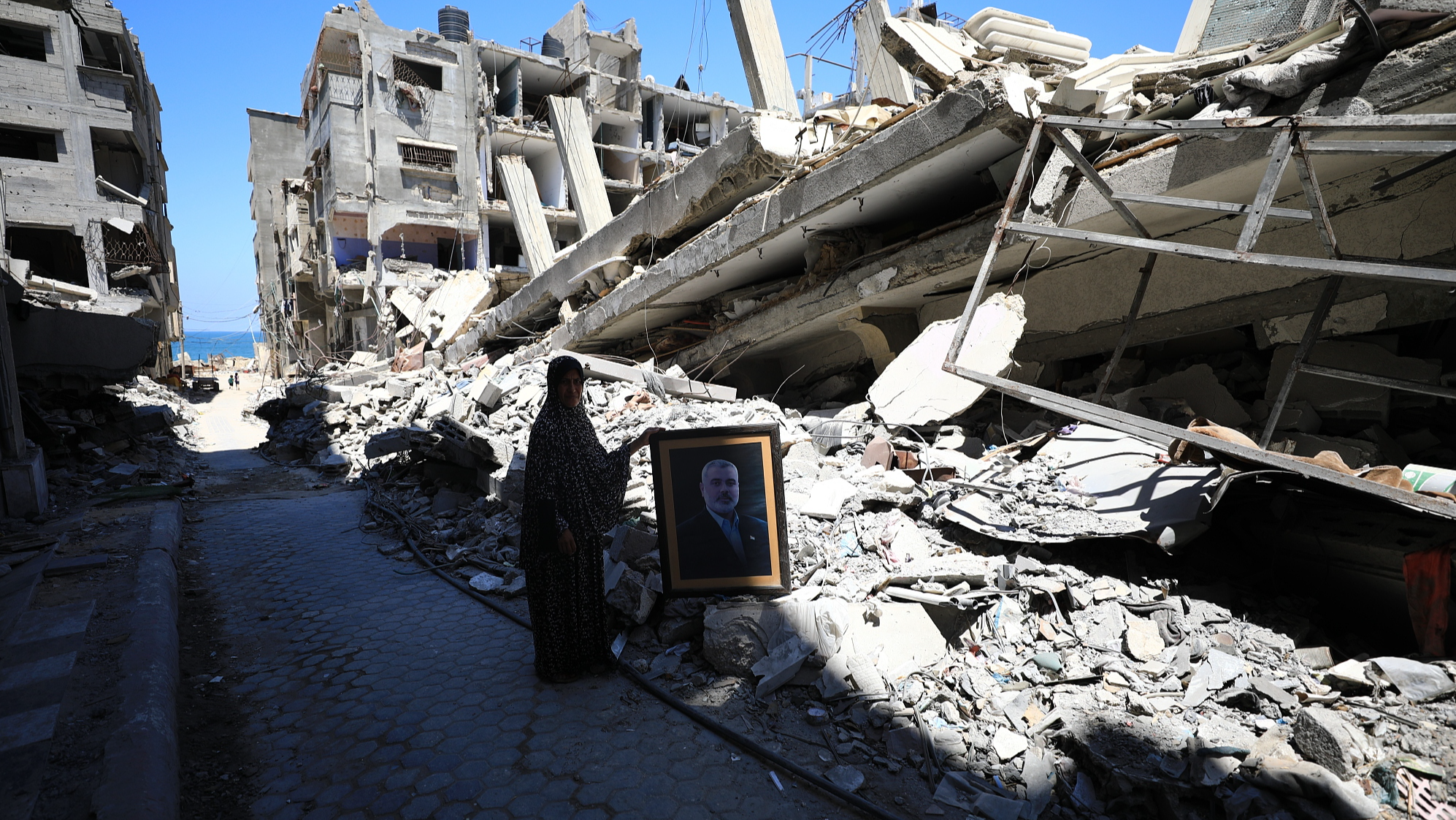 Palestinians carry the portrait of Hamas Political Bureau chief Ismail Haniyeh as they stand on the debris of a destroyed building, belonged to Ismail Haniyeh, following the Israeli attack in Al-Shati refugee camp of Gaza City, Gaza, July 31, 2024. /CFP