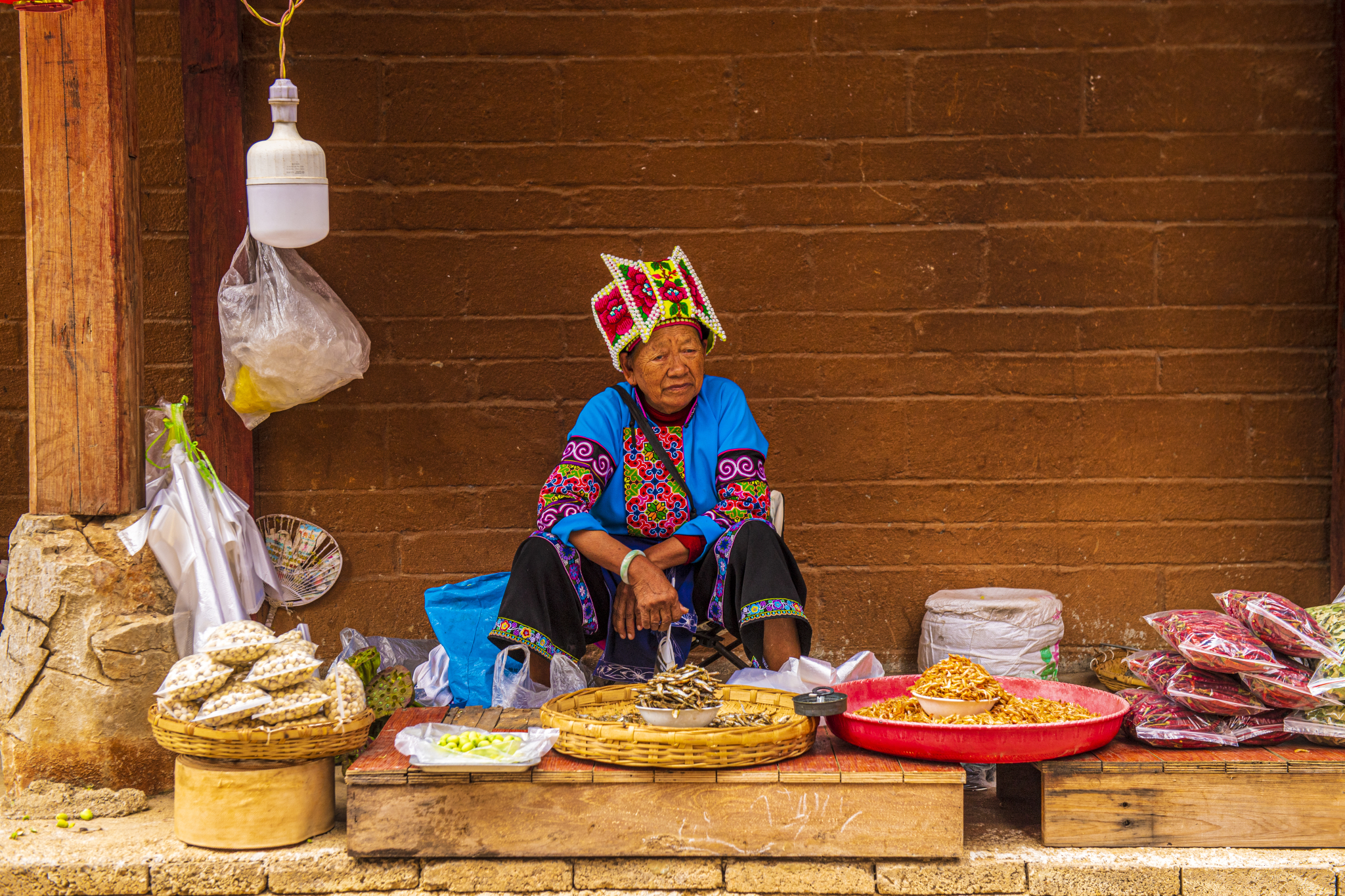 An elderly woman is seen selling snacks at Xianrendong Village in Yunnan Province on July 6, 2024. /CFP 