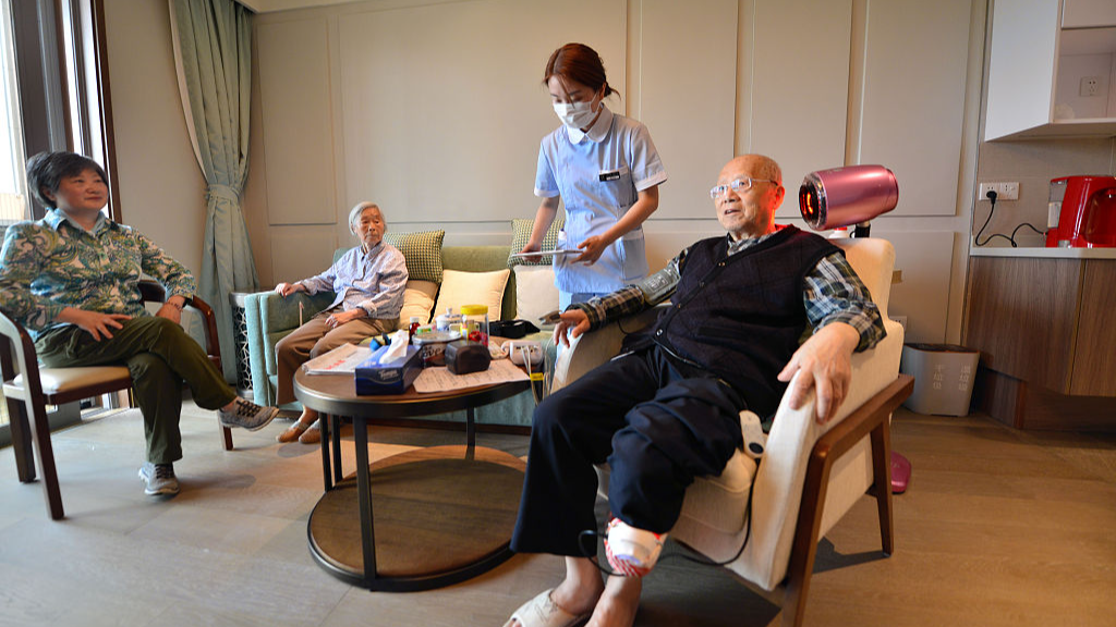 A medical worker checks on an elderly person at a senior care facility, Shanghai, May 20, 2020. /CFP
