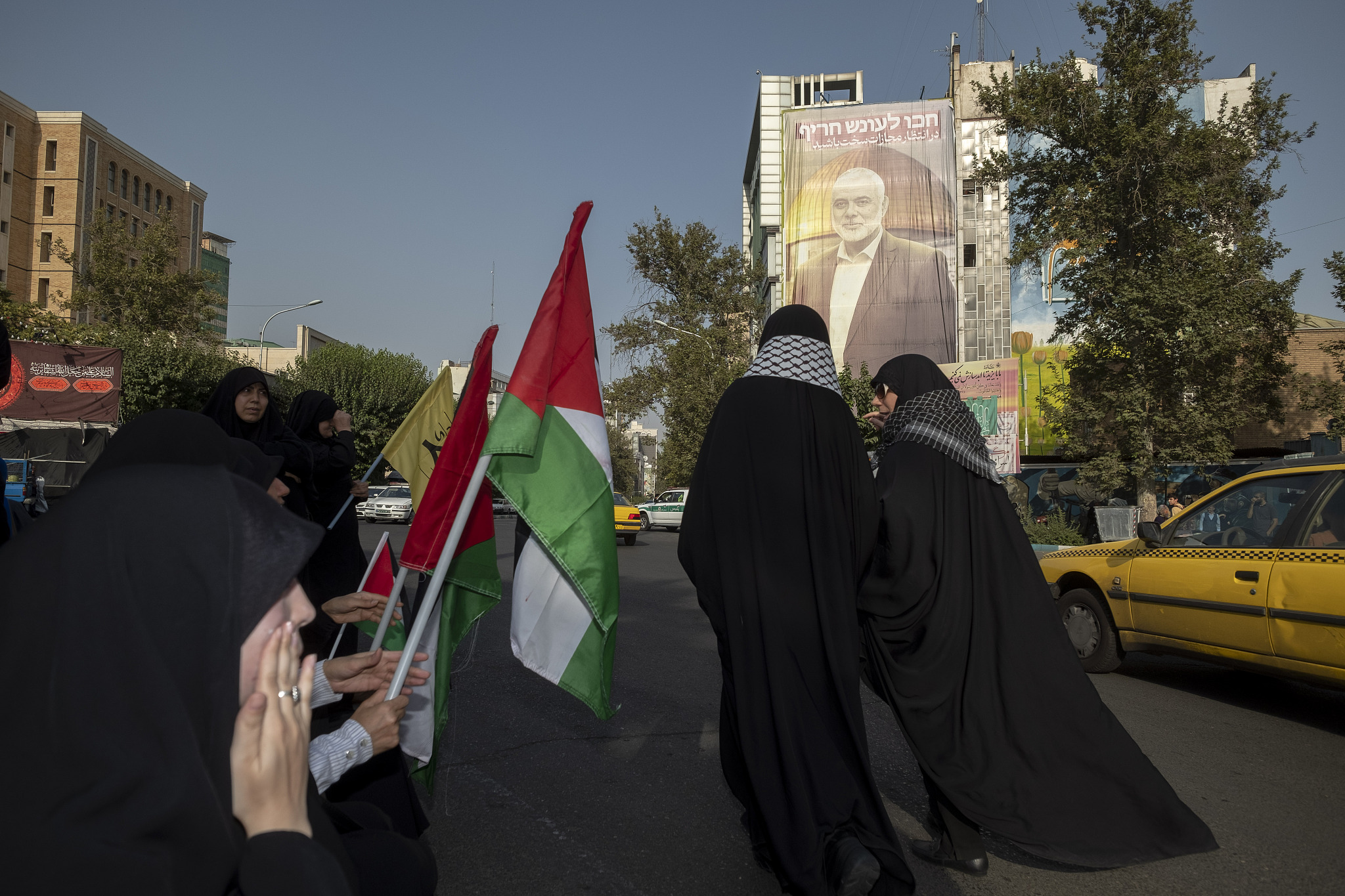 Veiled Iranian women hold Palestinian flags while sitting next to a portrait of Hamas' political leader Ismail Haniyeh, who was killed the day after the swearing-in ceremony of new Iranian President Masoud Pezeshkian, before a protest in Tehran, Iran, July 31, 2024. /CFP