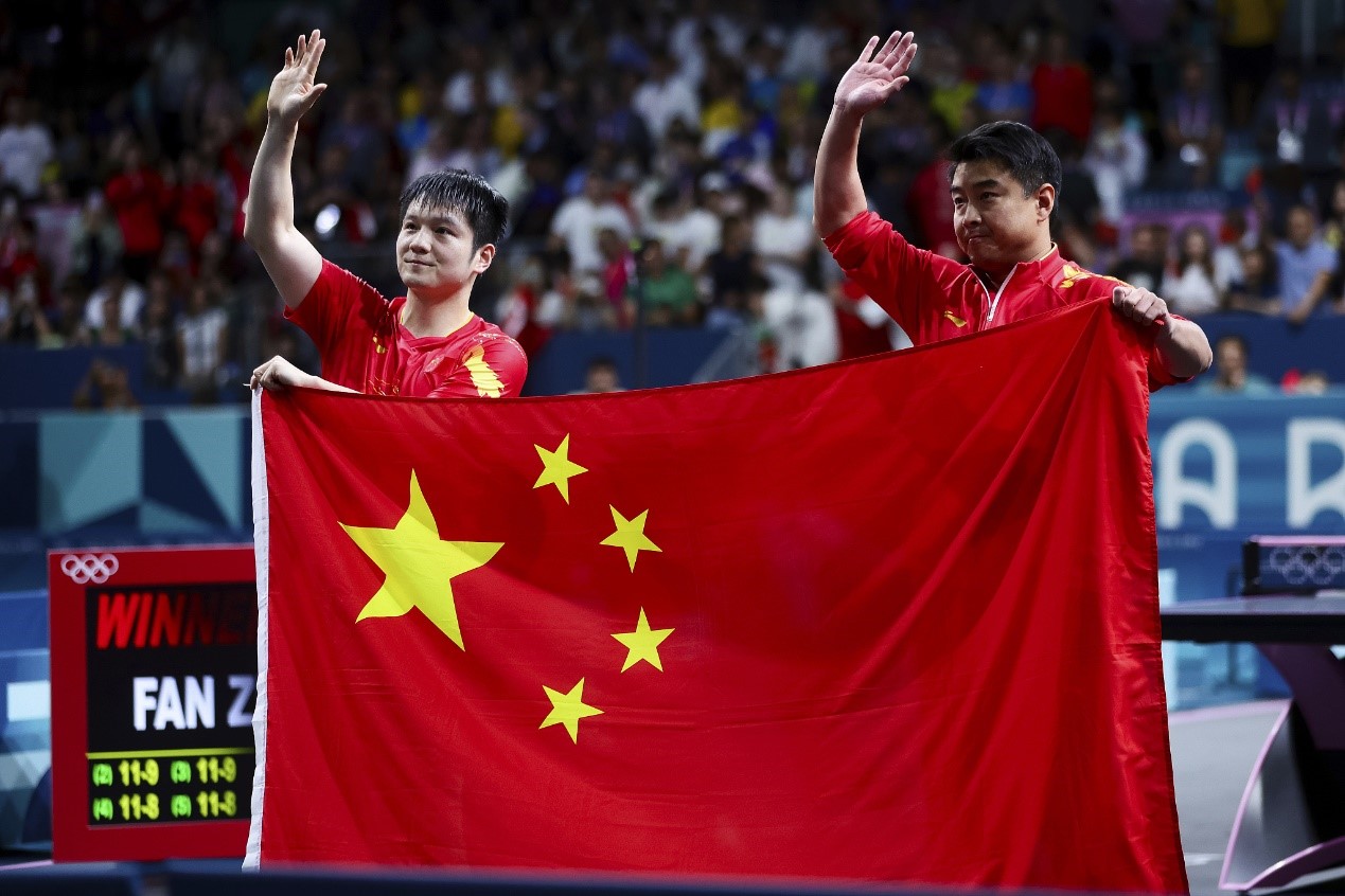 China's Fan Zhendong (L) and coach Wang Hao acknowledge the fans after Fan's victory in the men's singles table tennis final at the 2024 Summer Olympics at South Paris Arena 4 in Paris, France, August 4, 2024. /CFP