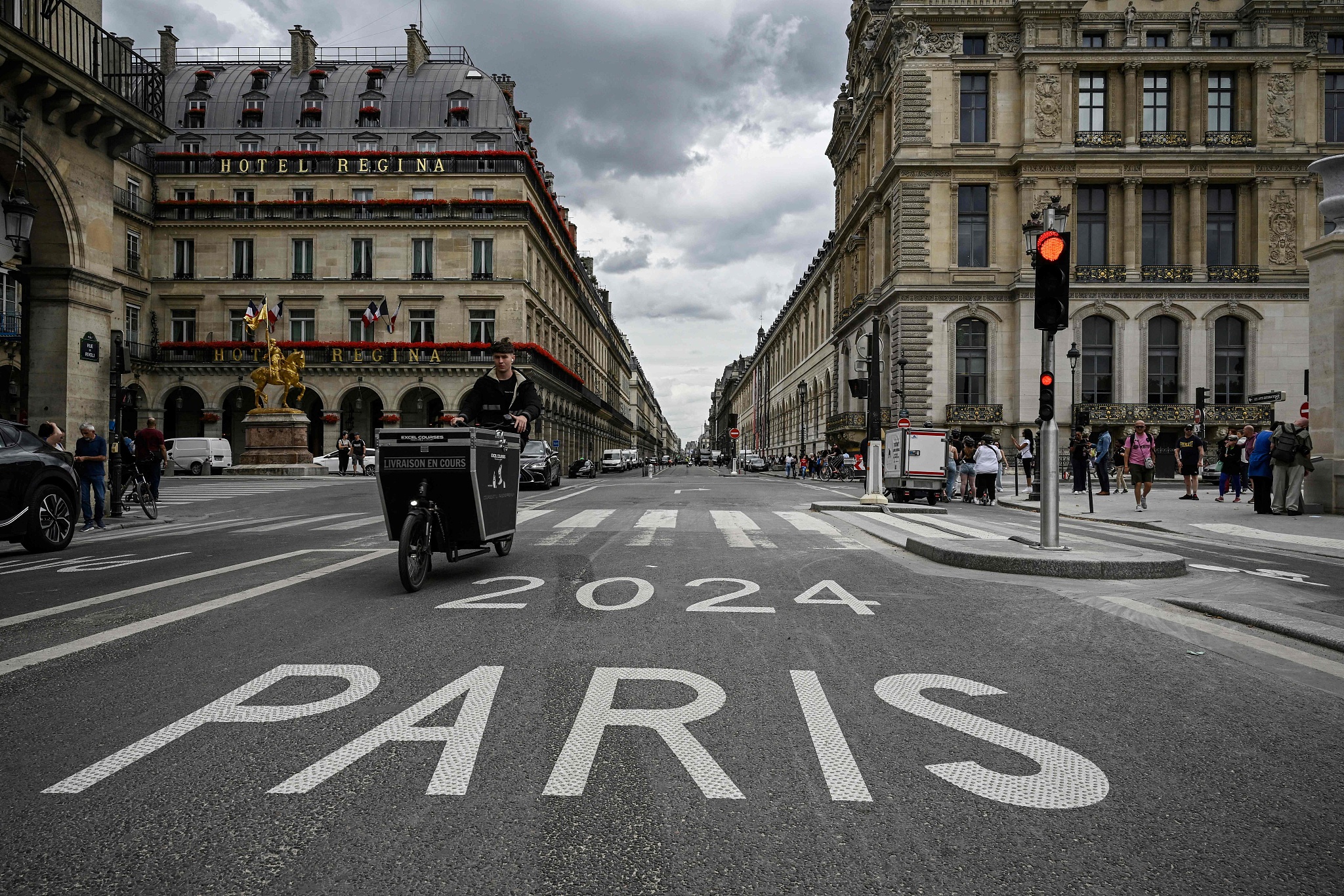 A delivery man rides past a road sign of a 