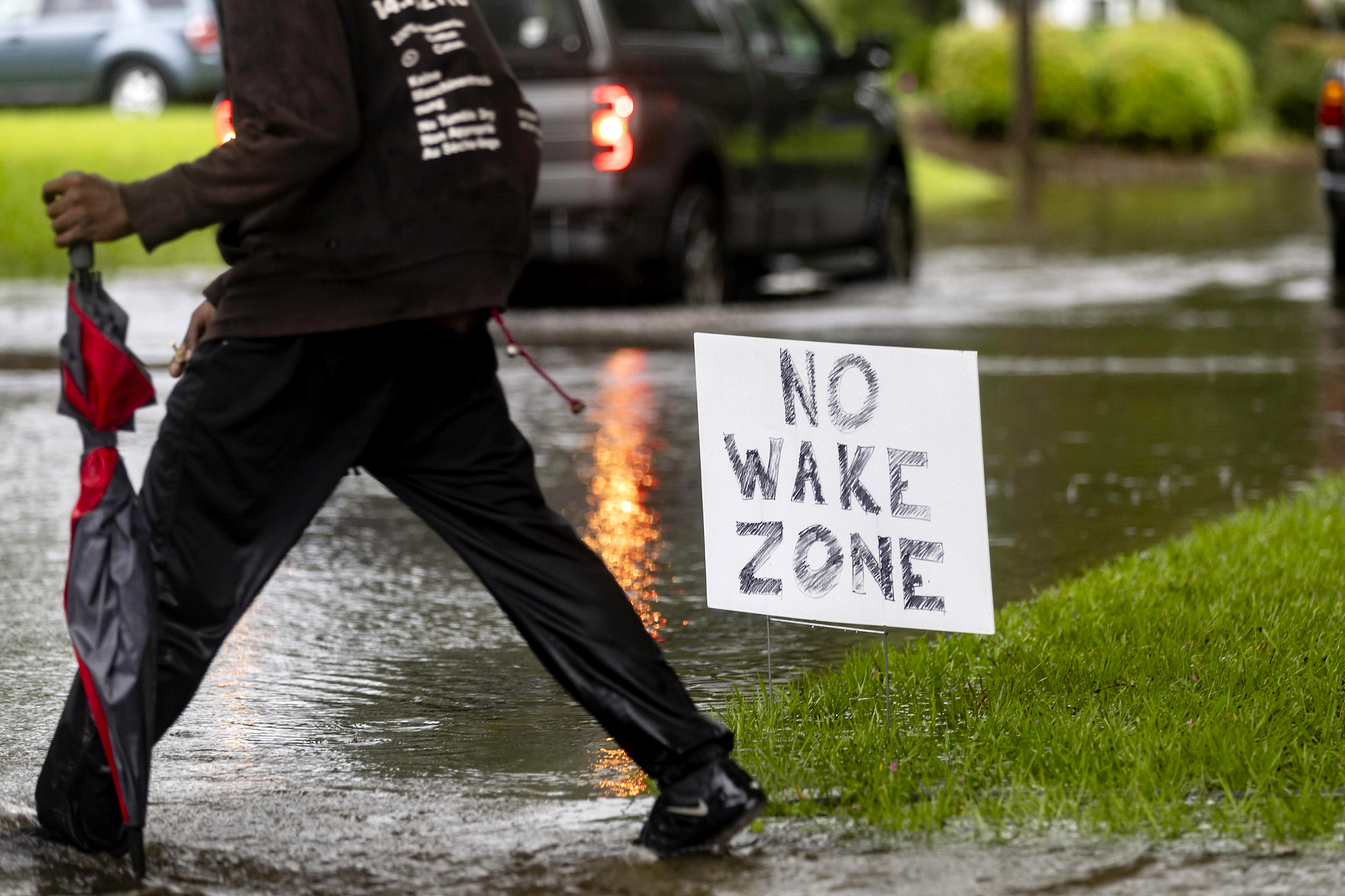 A pedestrian walks past a sign on a flooded street after heavy rain from Tropical Storm Debby, in Savannah, U.S., August 5, 2024. /CFP