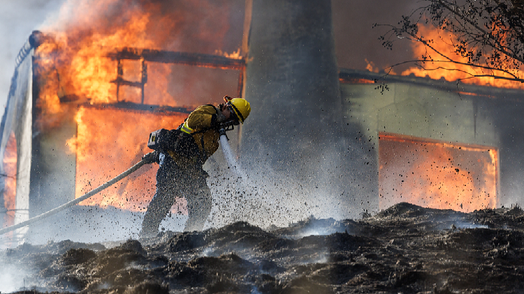 Rapidly spreading wildfire consumes residences in Southern California