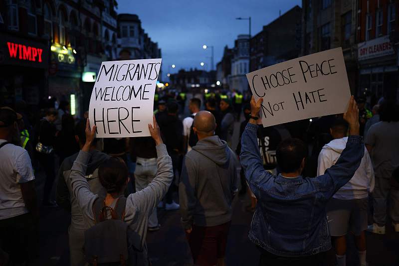 Orang-orang memegang plakat antirasisme selama demonstrasi tandingan terhadap protes antiimigrasi yang diserukan oleh aktivis sayap kanan, di dekat kantor Pengacara Imigrasi di Westcliff, dekat Southend-on-Sea, Inggris timur, 7 Agustus 2024. /CFP