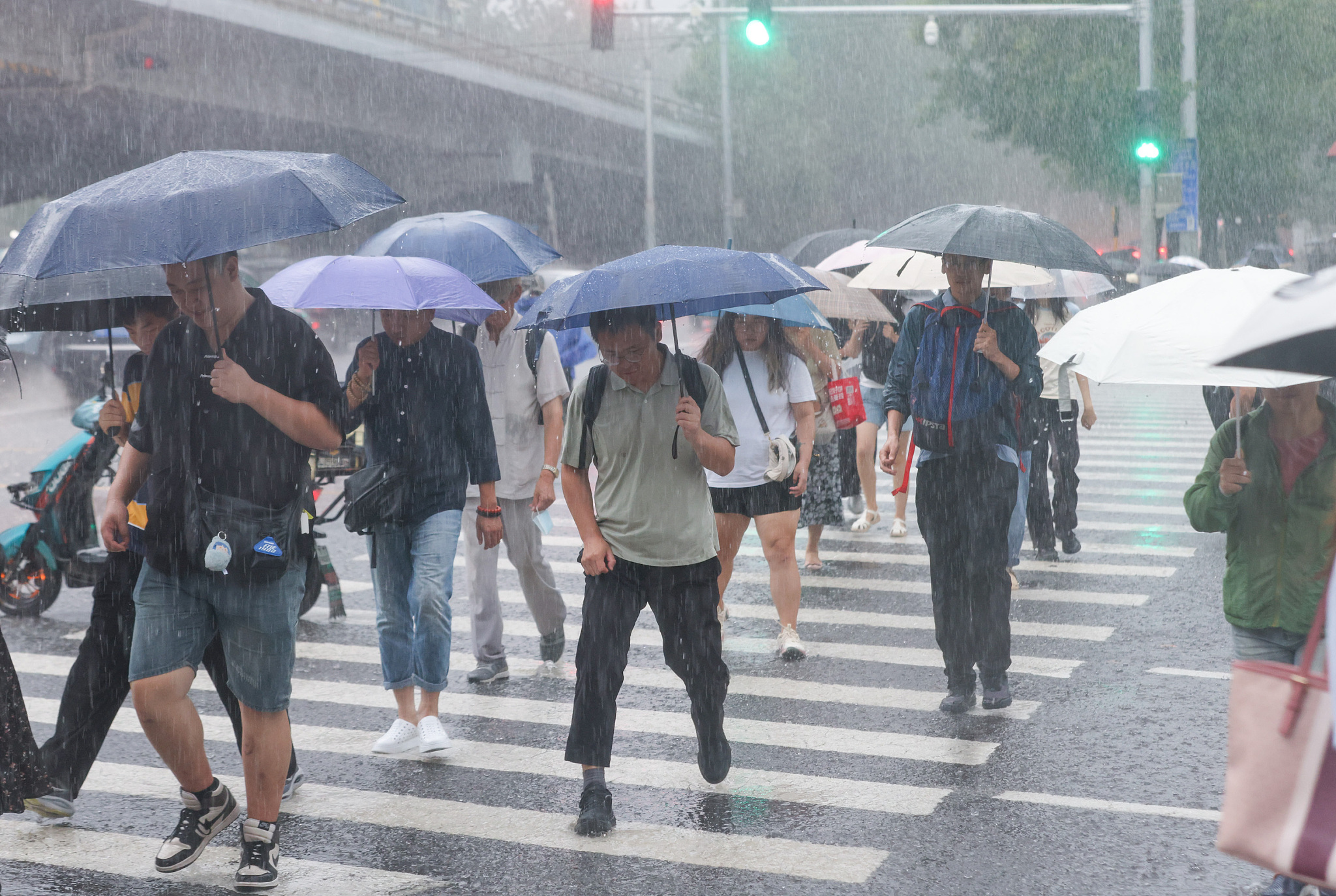 People walk amid heavy rains in the evening in Beijing, China, August 9, 2024. /CFP