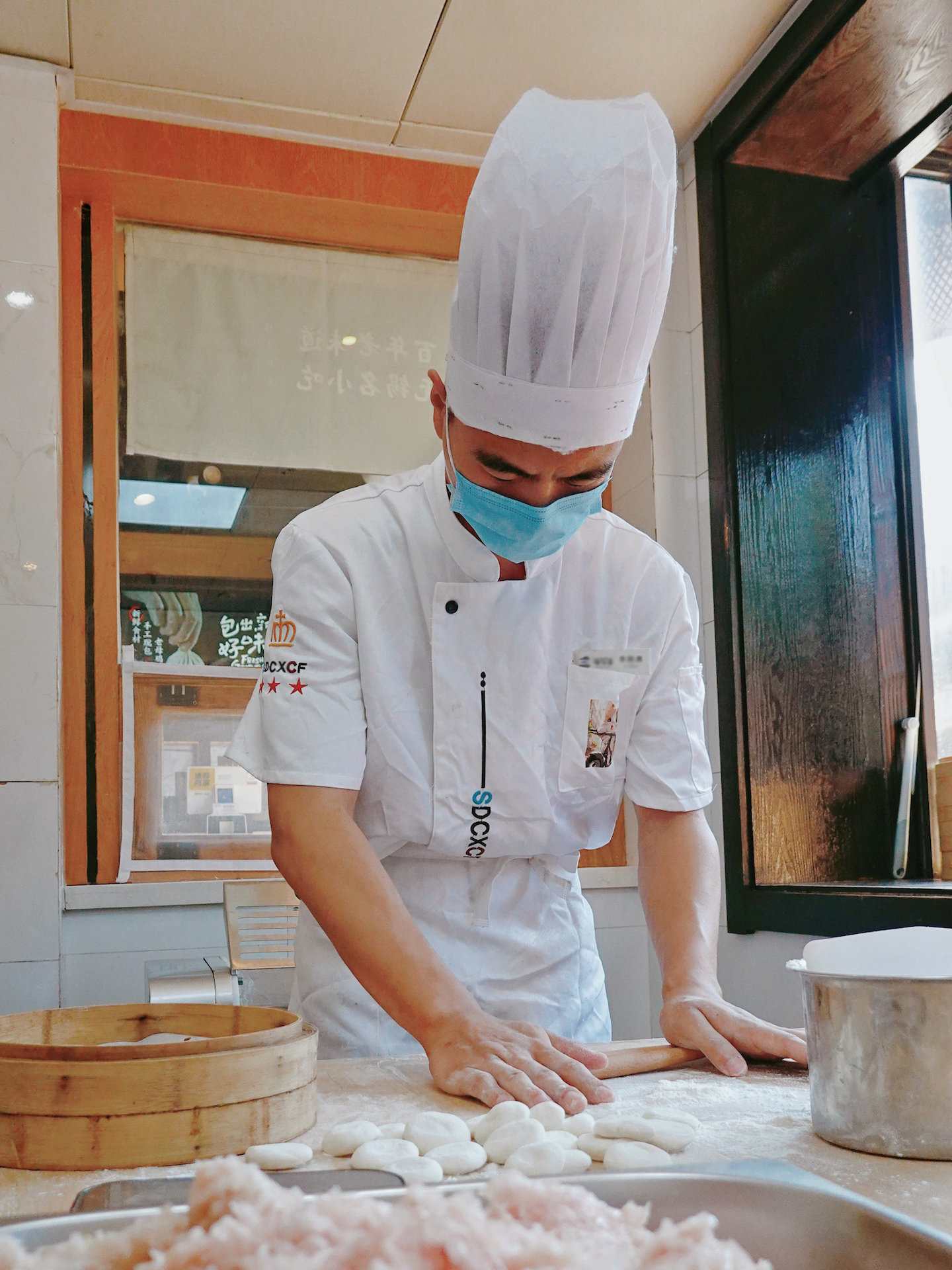 A chef rolls the dough into wrappers for Wuxi-style steamed buns. /CGTN