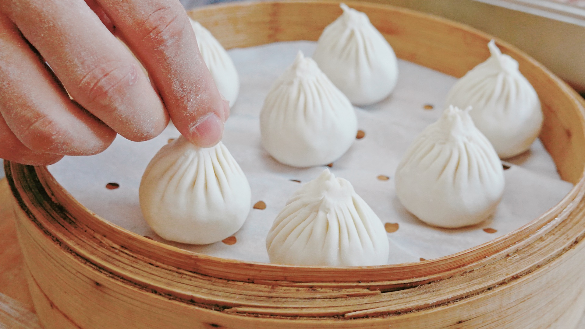 A chef places the Wuxi-style steamed buns onto a bamboo steamer basket. /CGTN