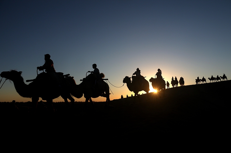 Visitors enjoy beautiful views of dusk at the Mingsha Mountain and Crescent Spring scenic spot in Dunhuang City, Gansu Province, August 9, 2024. /CFP